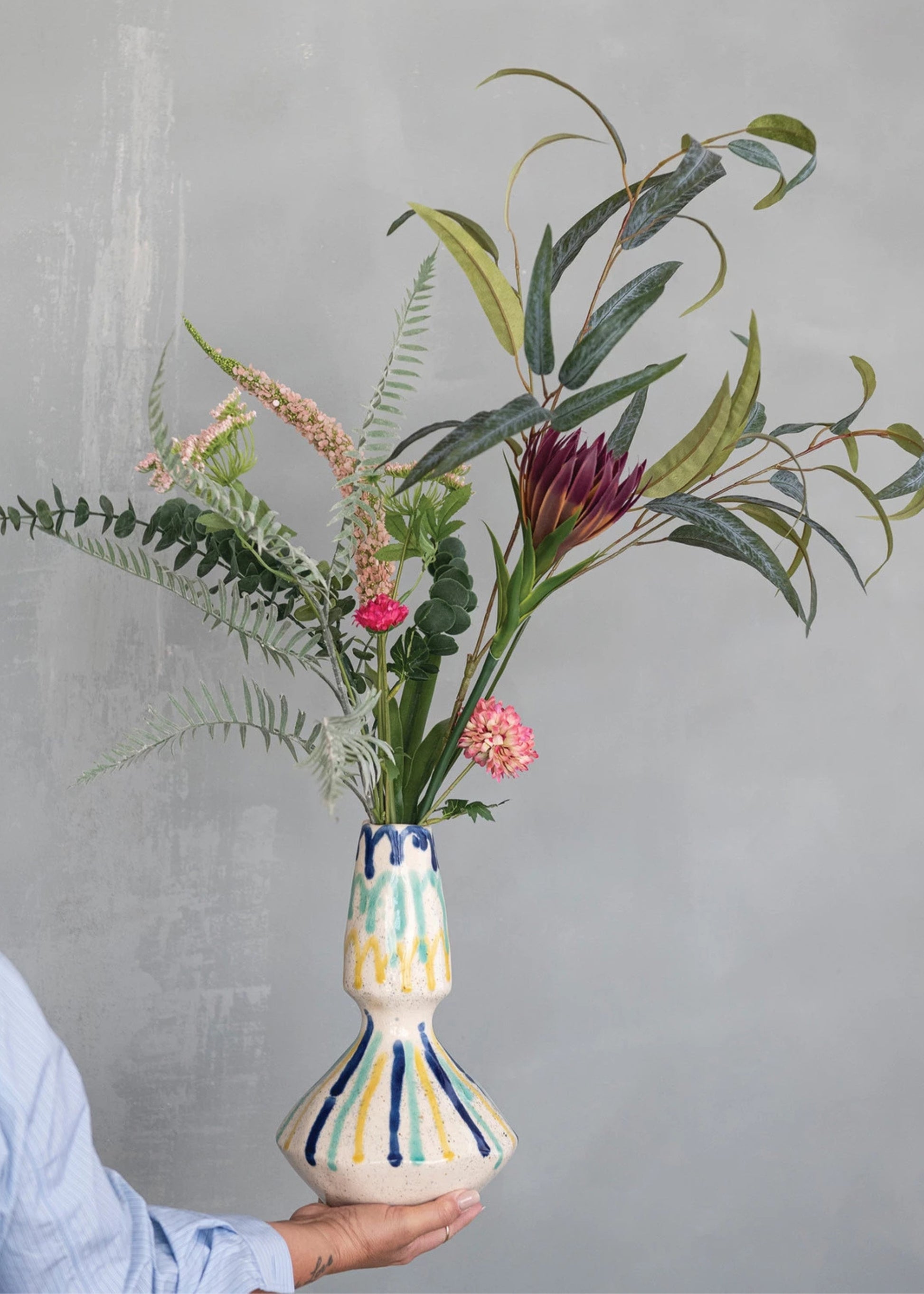 Person holding a colorful vase with flowers 
