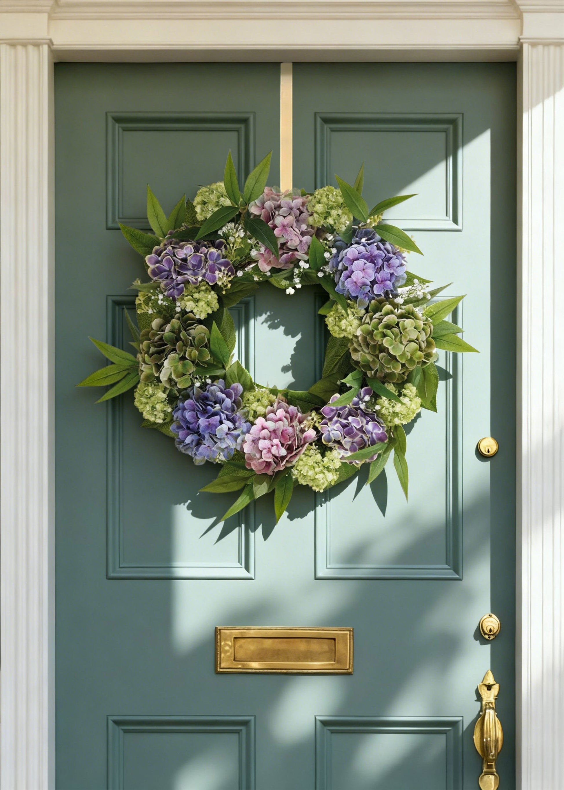 Floral wreath on a teal door with gold mail slot and handle