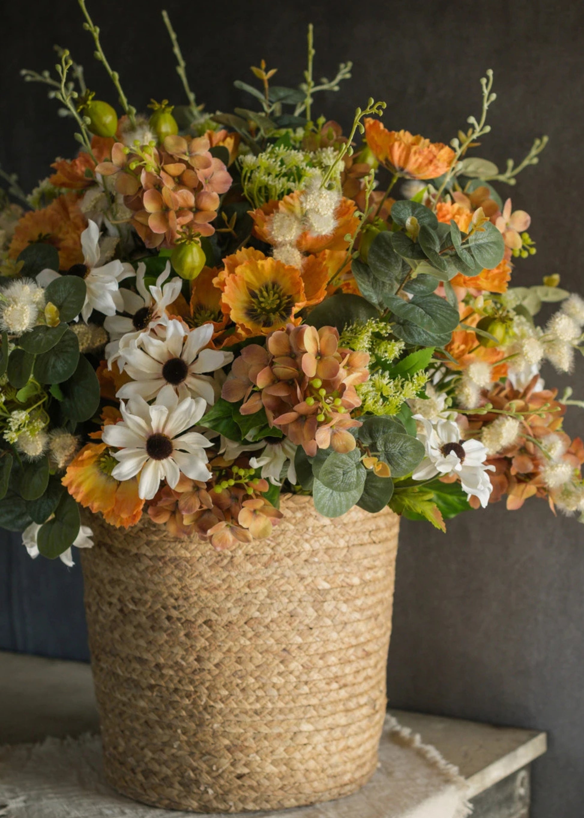 Bouquet of orange artificial flowers in a woven basket 