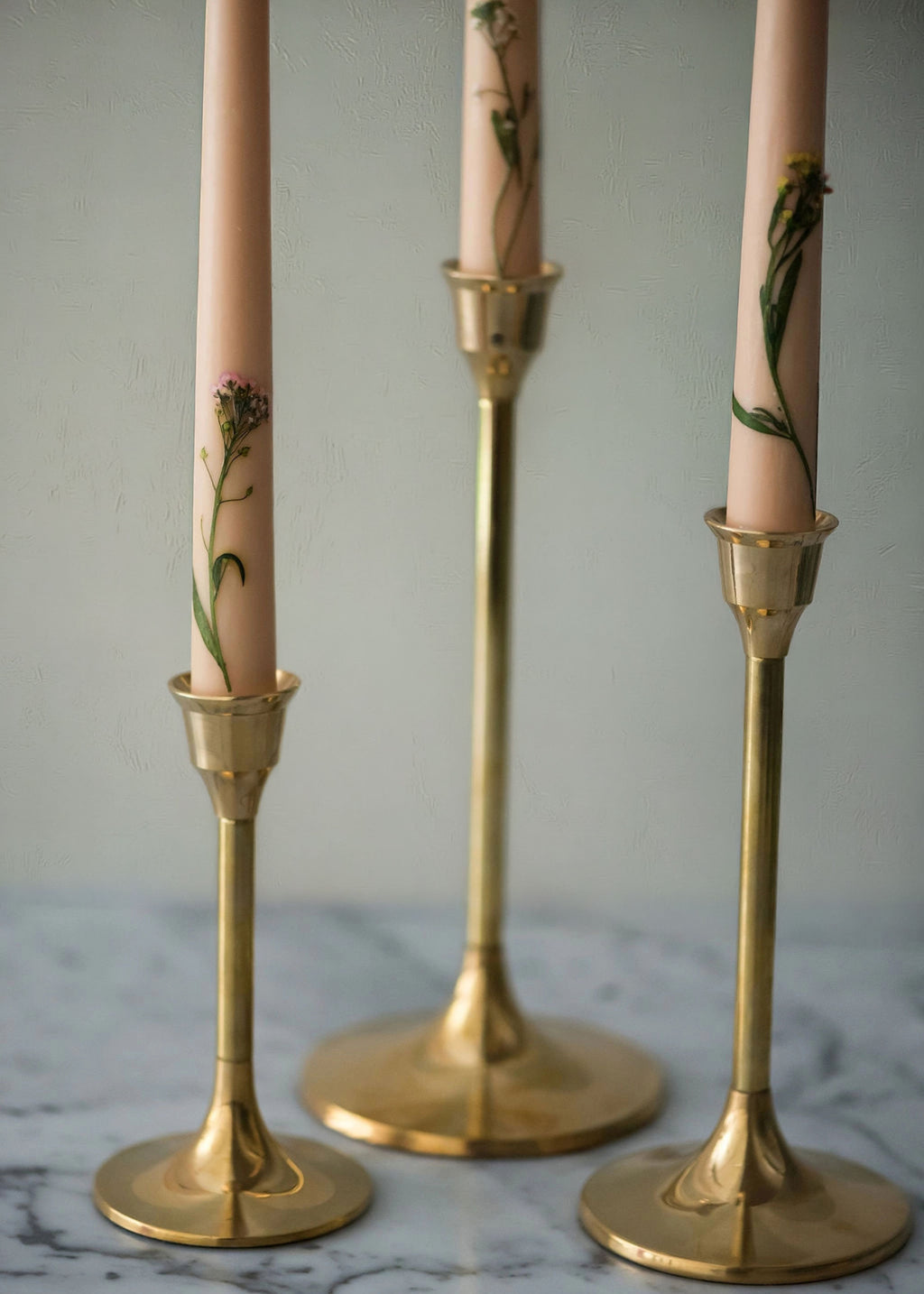 Close-up of floral beeswax candles in gold candle holders