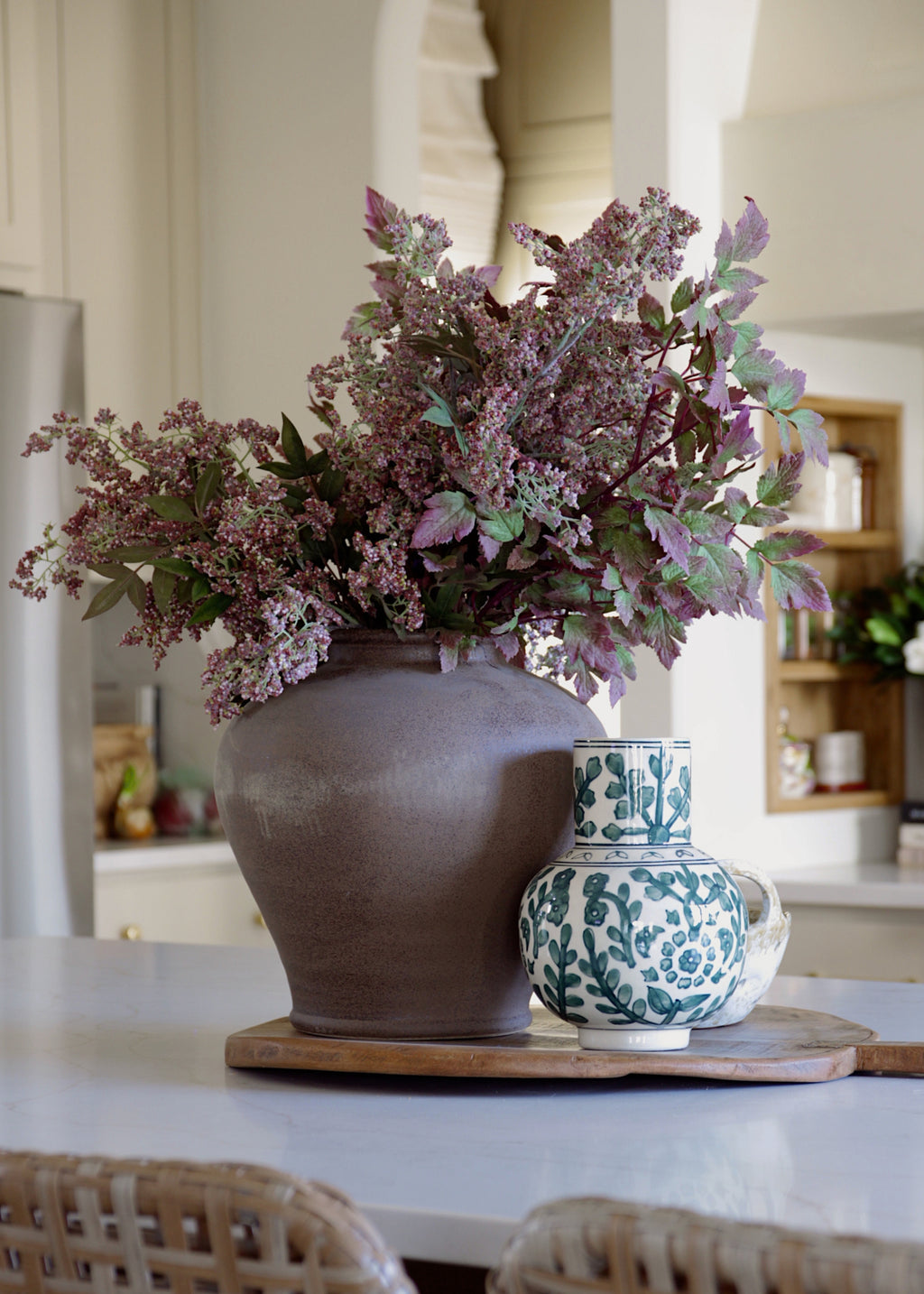 mauve plum berries and cimicifuga arranged in a stoneware vase