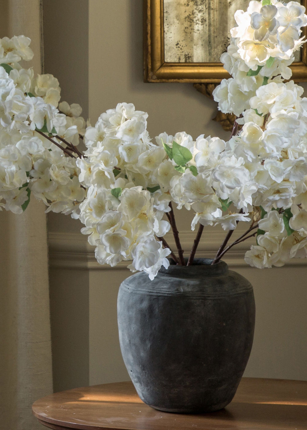 close-up of artificial cherry blossom stems in concrete vase
