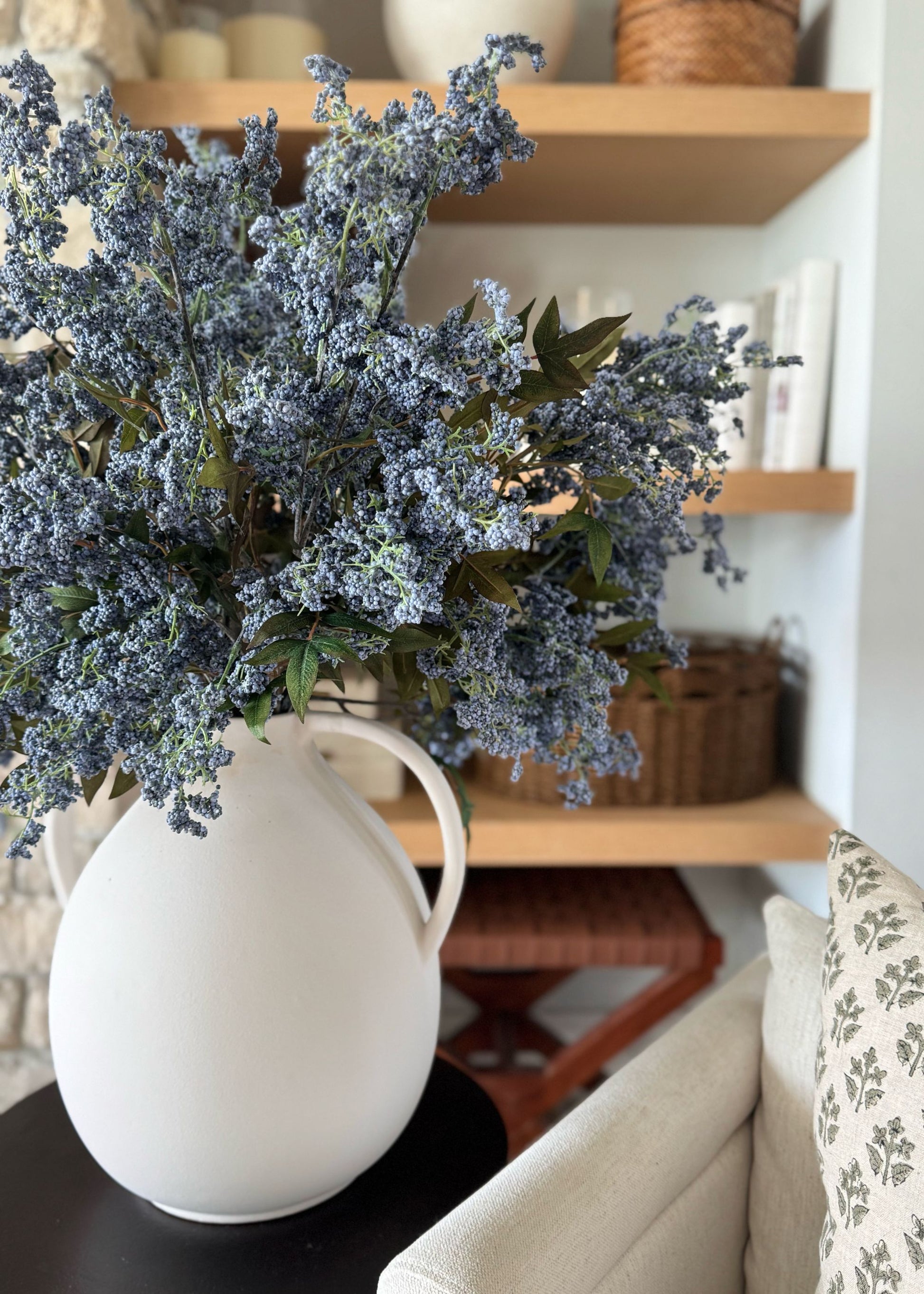 blue plum berry branches styled in white jug vase