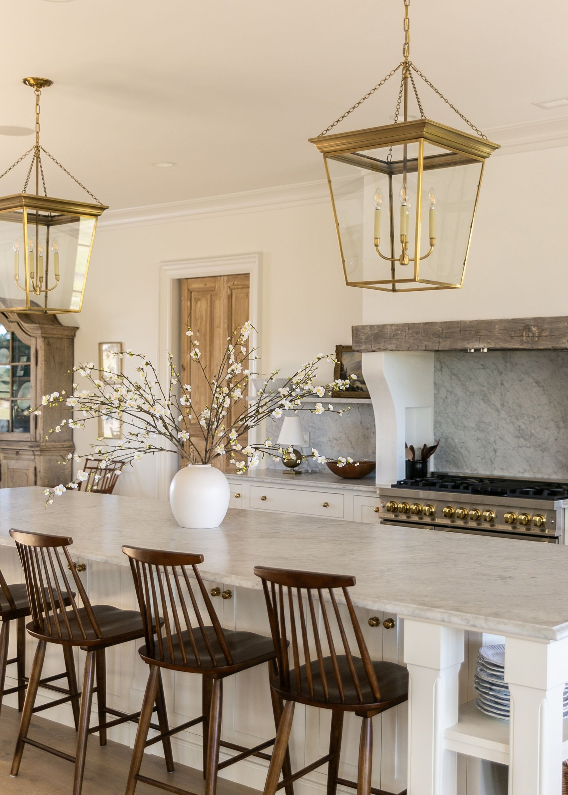Modern kitchen island with large statement flower arrangment of cream blossom branches and stoneware vase
