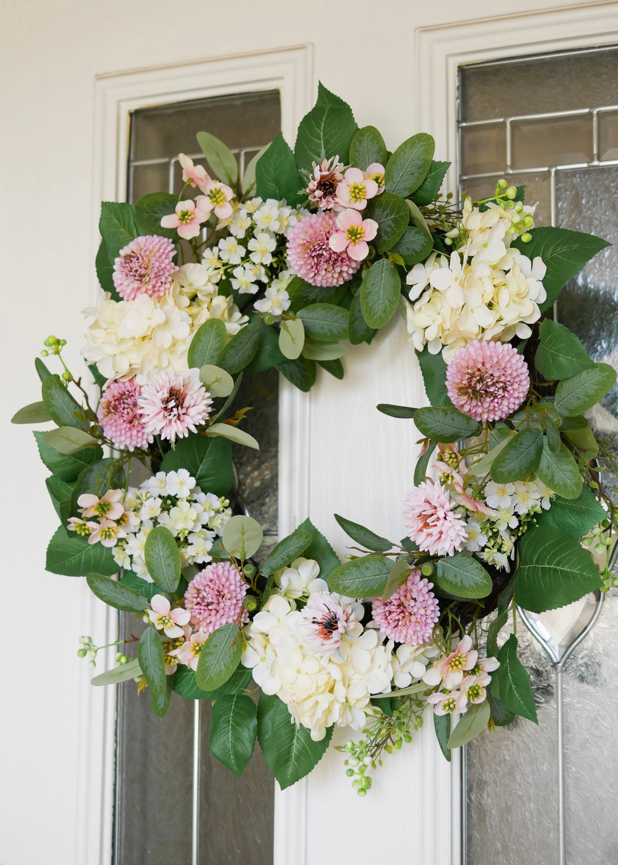 Floral wreath with pink, white, and green flowers on a door