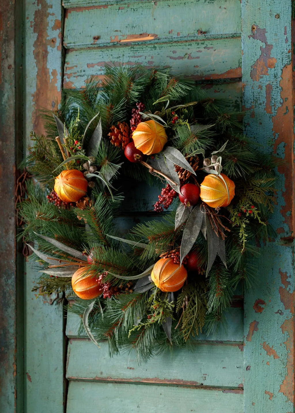 Decorative wreath with pumpkins and berries on a rustic wooden door