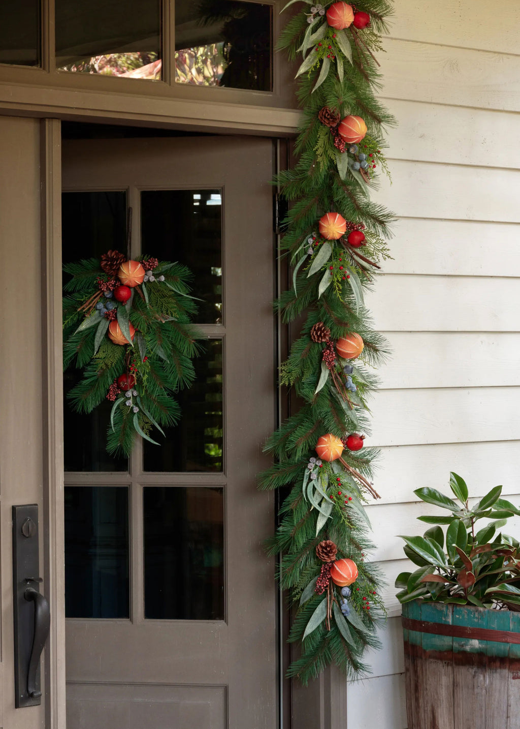 doorway draped in a holiday evergreen garland with dried orange and berry accents