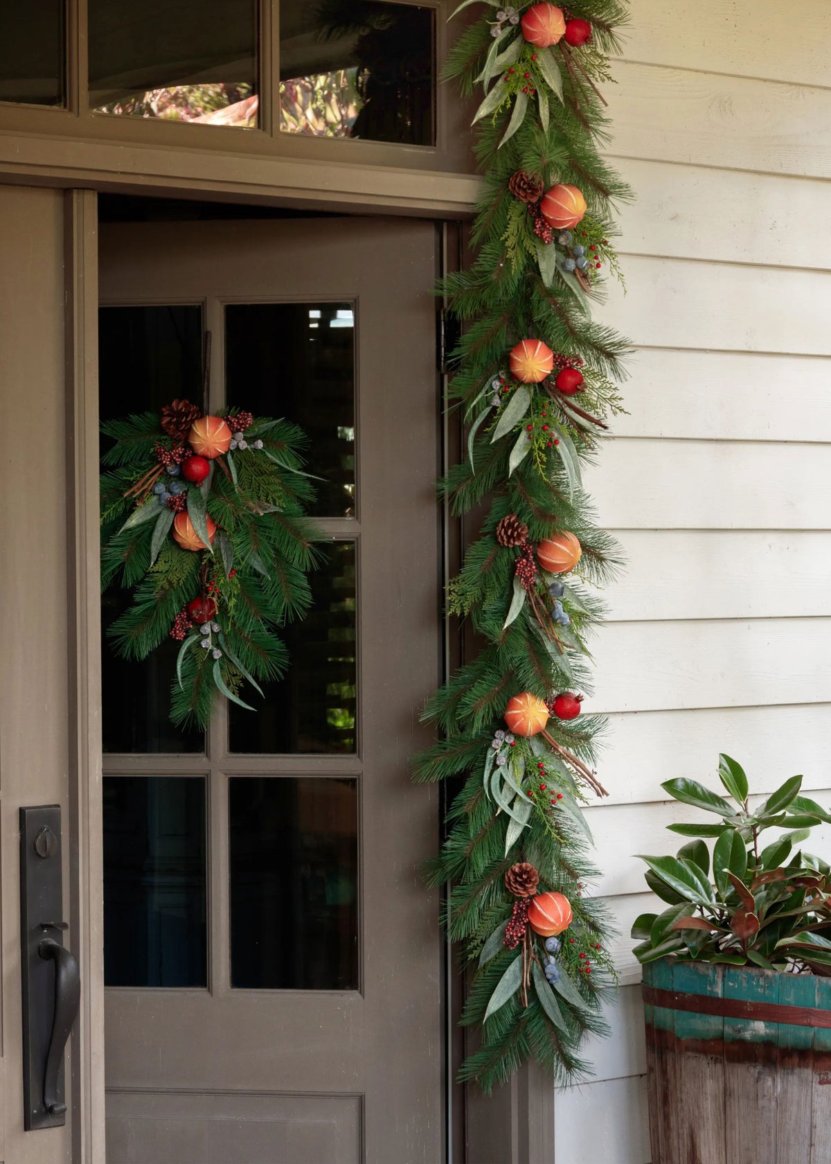 doorway draped in a holiday evergreen garland with dried orange and berry accents
