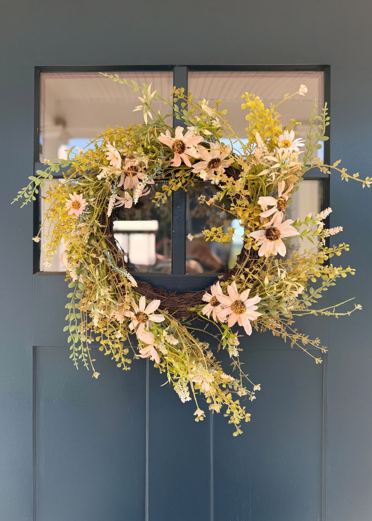 pale pink daisy wreath on a blue door