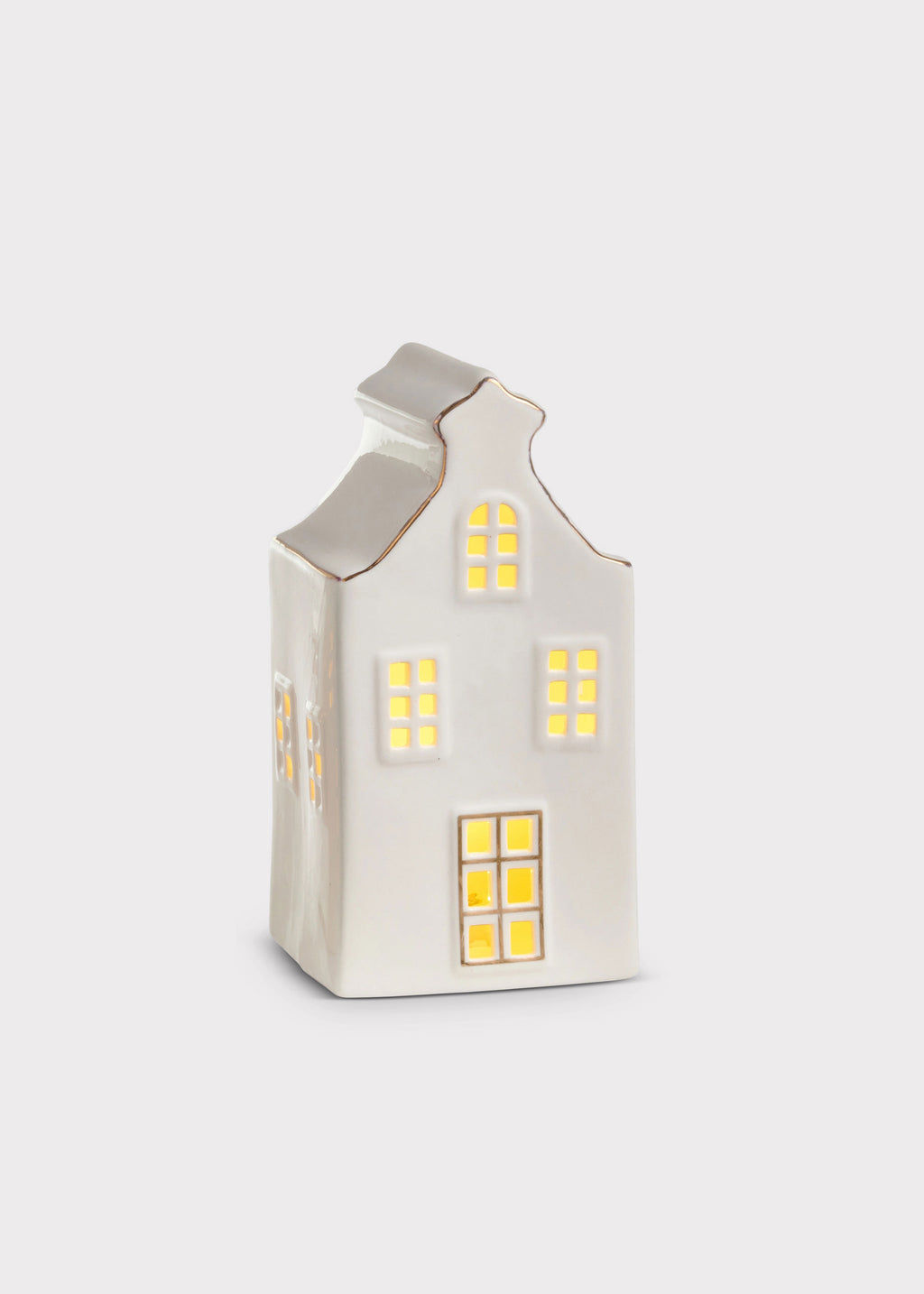 A small white ceramic house-shaped candle holder with glowing yellow window lights, set against a plain light gray background.