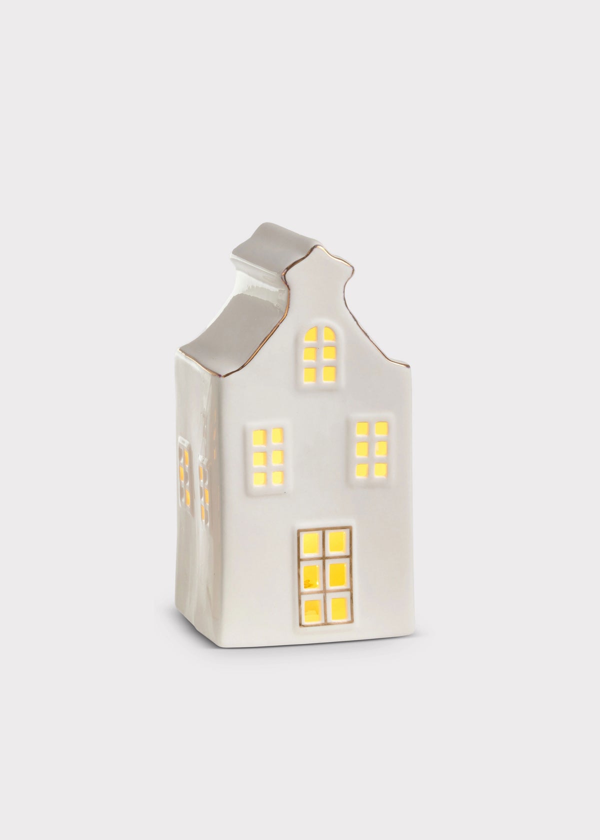 A small white ceramic house-shaped candle holder with glowing yellow window lights, set against a plain light gray background.