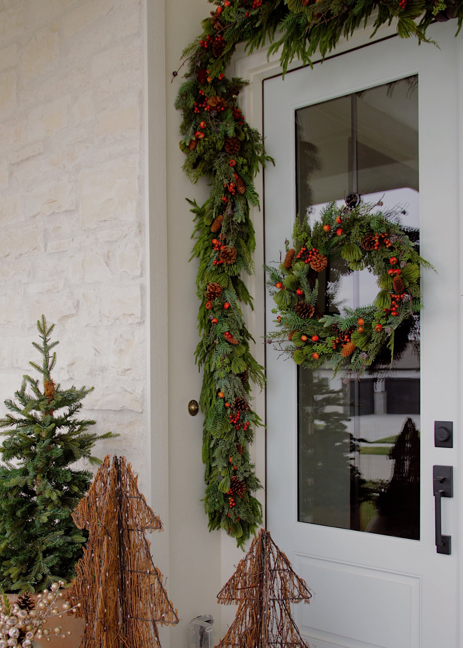 Decorative Christmas wreath and garland on a door with pine cones and berries