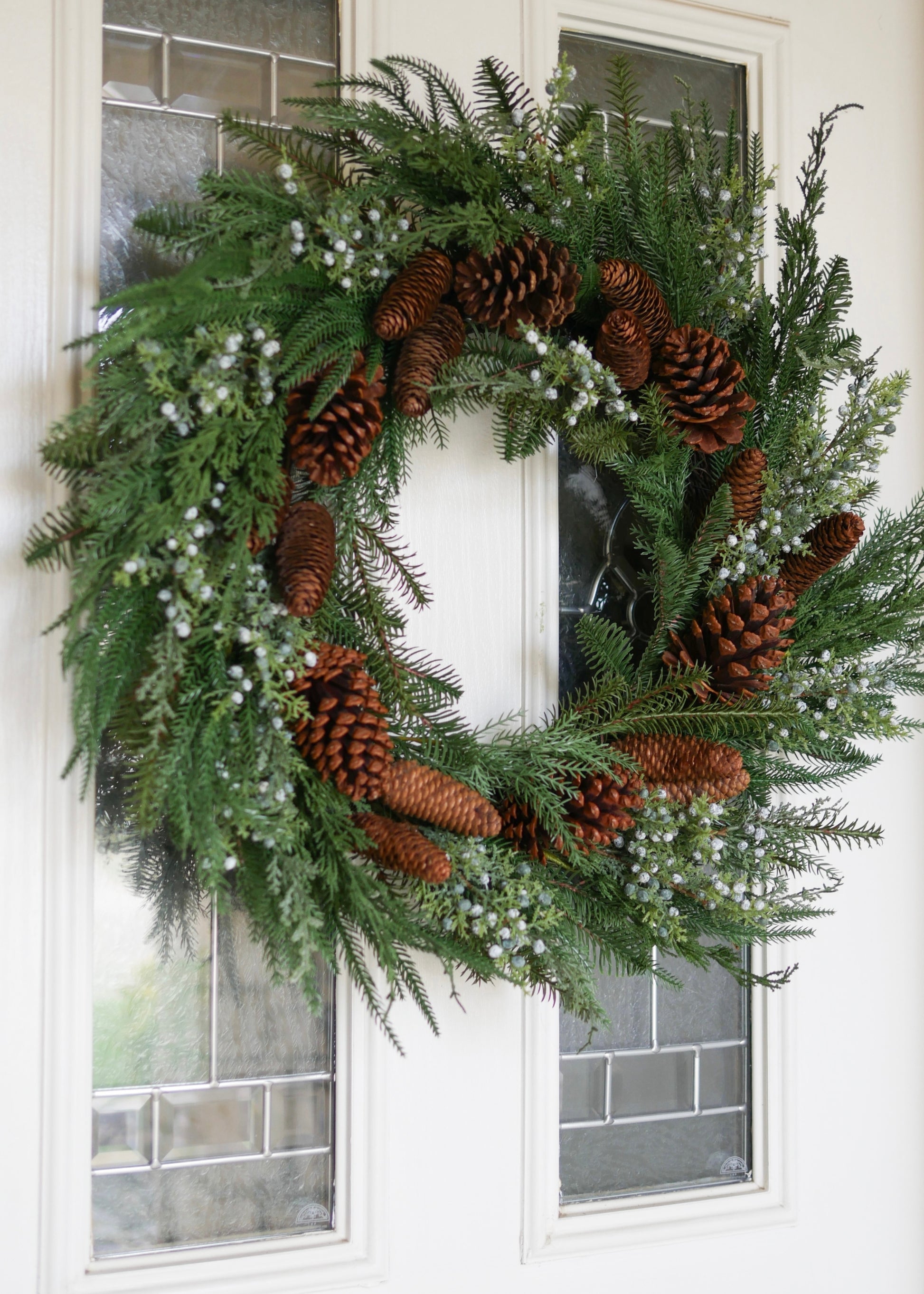 Fake Winter Greenery Wreath with Berries and Pine Cones on White Door