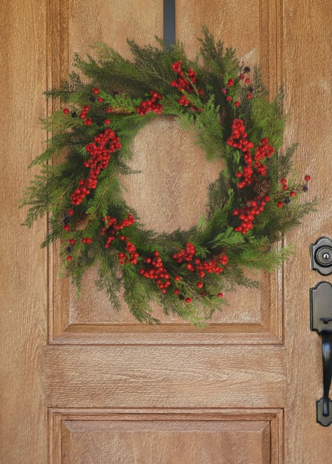 Faux cedar wreath with red berries on wood door