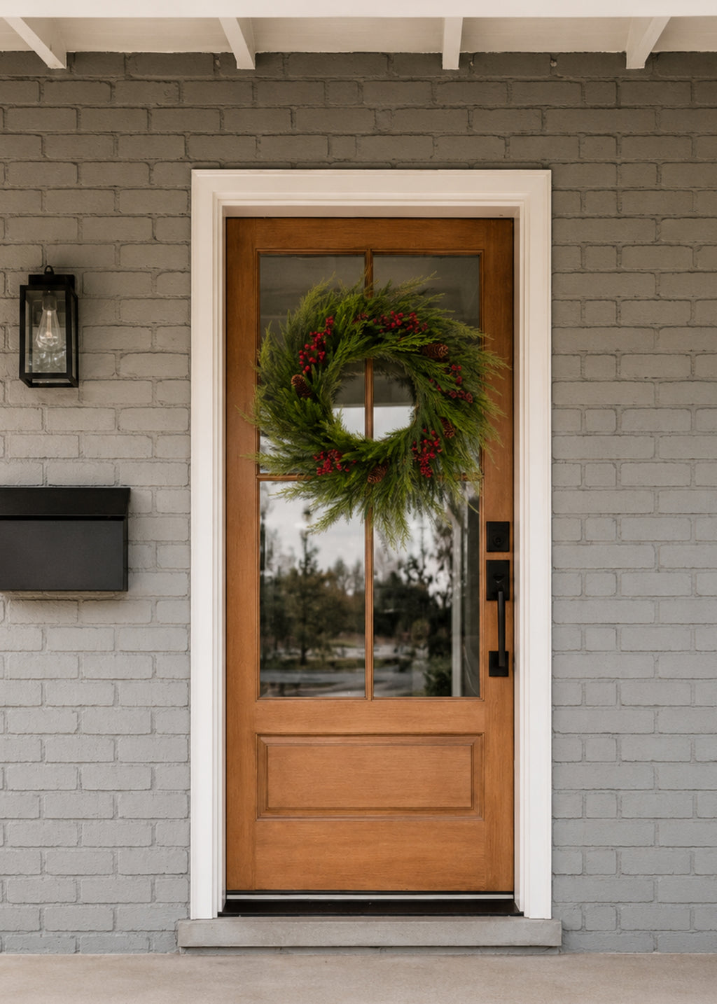 evergreen wreath with red berries on wood and glass door