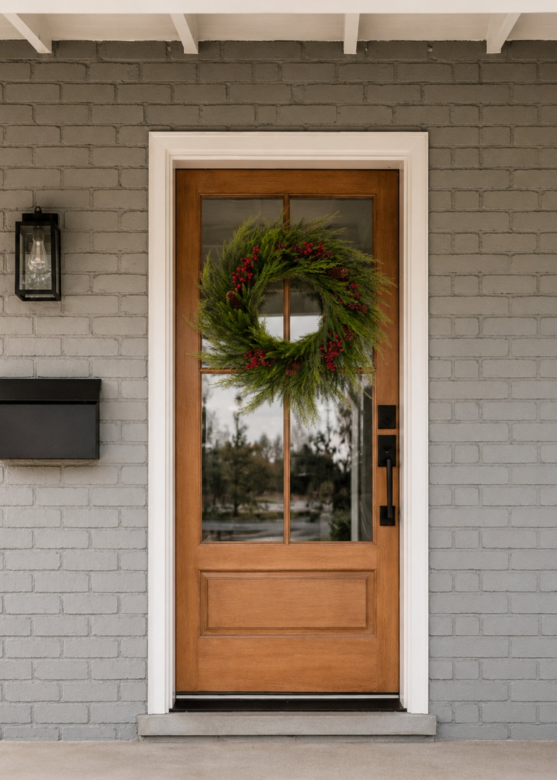 evergreen wreath with red berries on wood and glass door