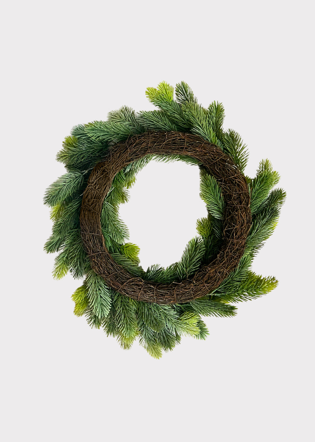 the back of a circular holiday wreath made of green pine branches around a rustic brown grapevine base