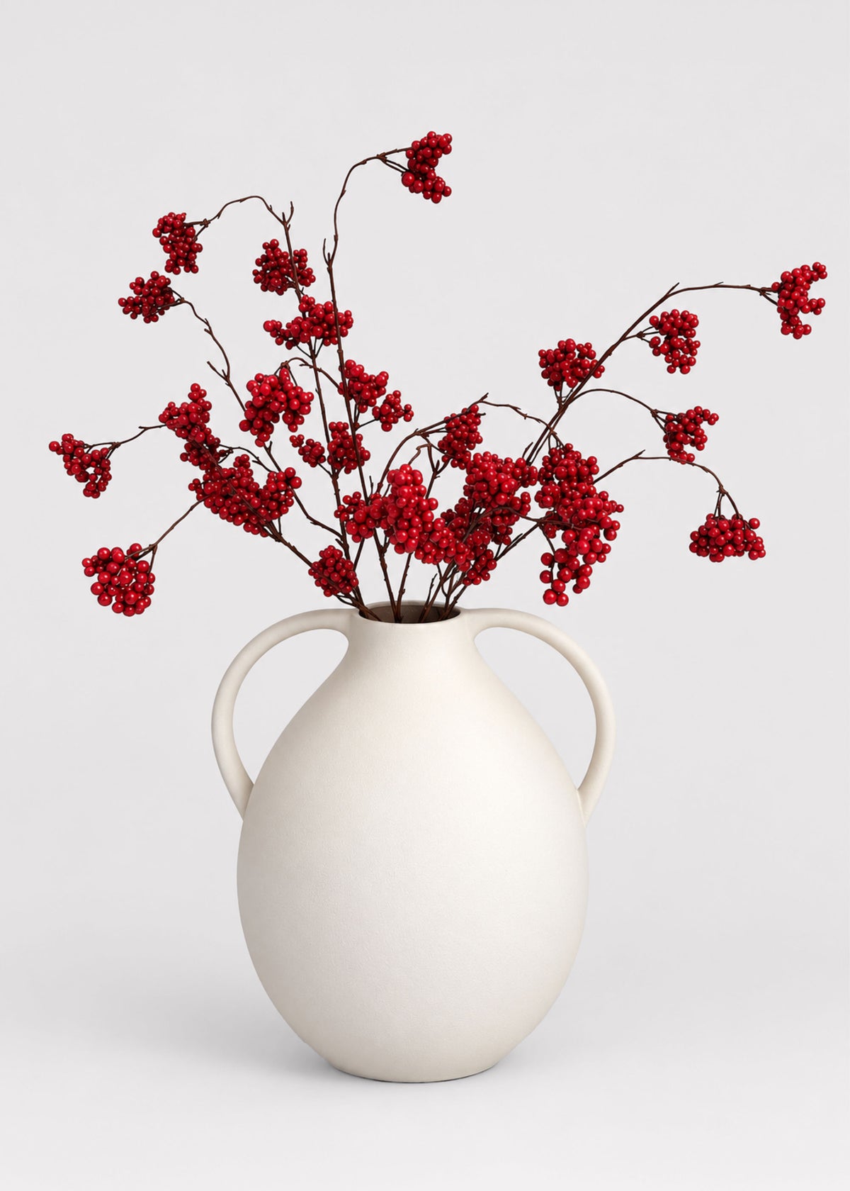 red berries arranged in a white vase