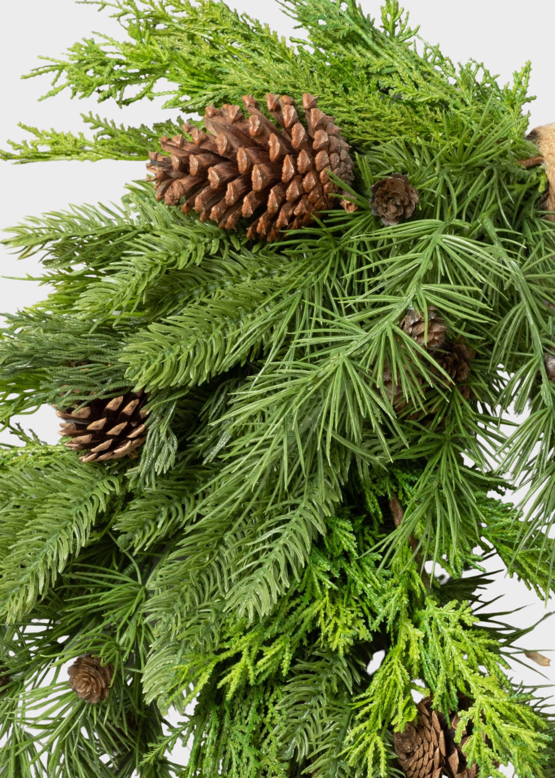 A close-up of a green evergreen wresth with pinecones 