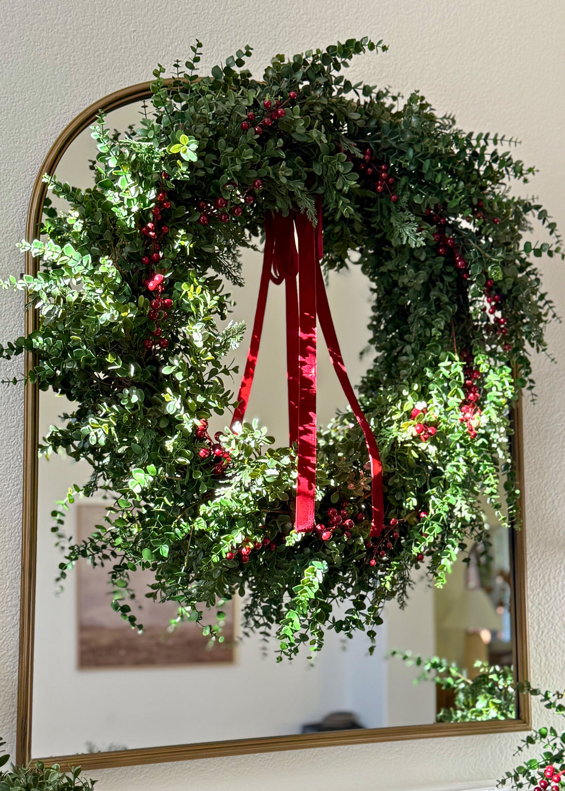 eucalyptus and red berry wreath hung on a mirror