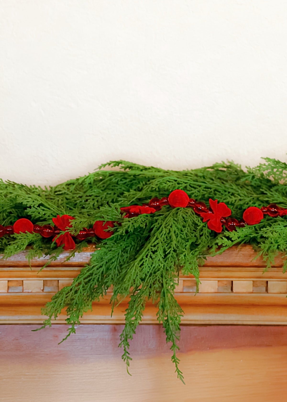 red holiday bow tie garland on cedar 