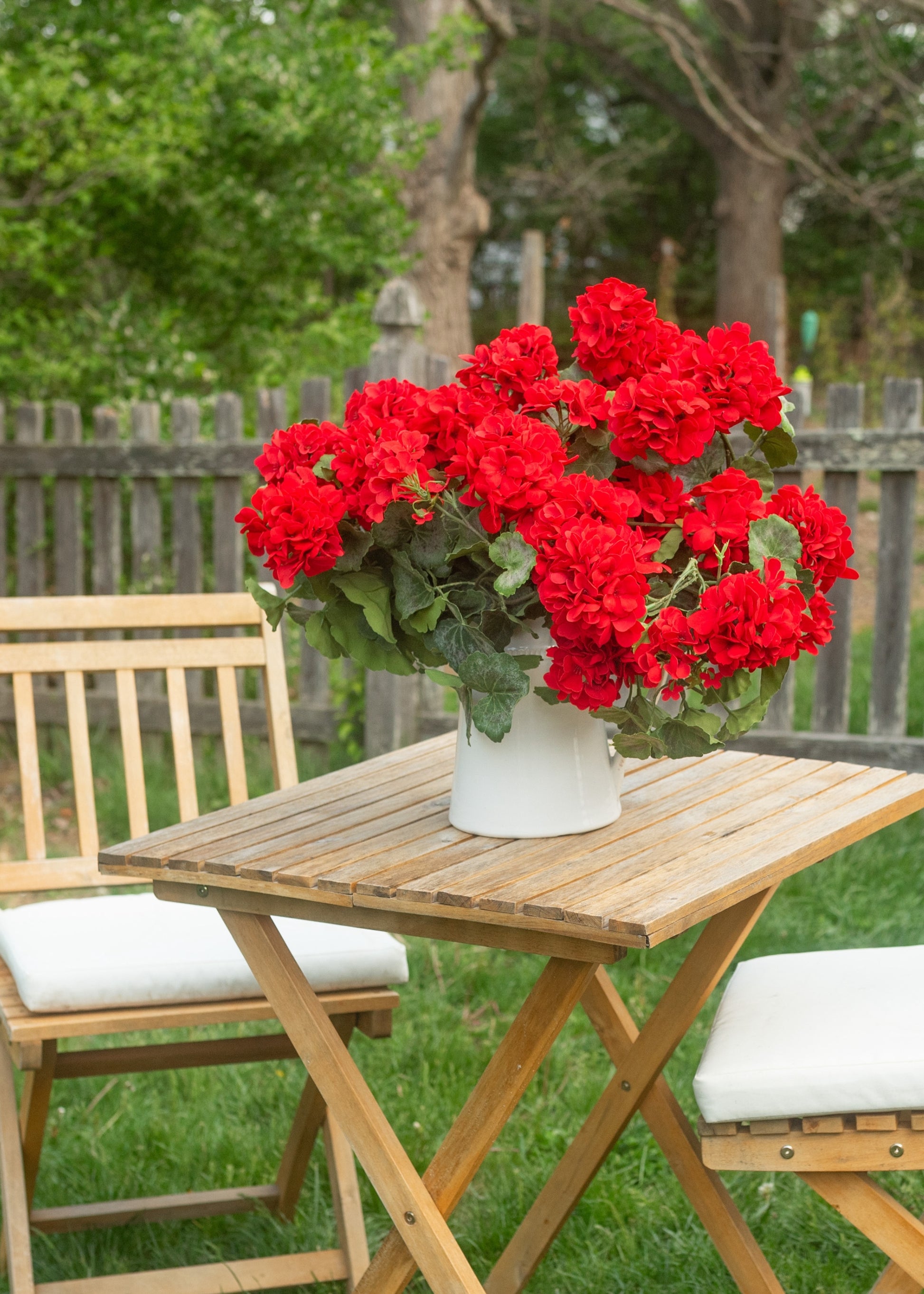 artificial red geraniums styled in a pot on an outdoor cafe table