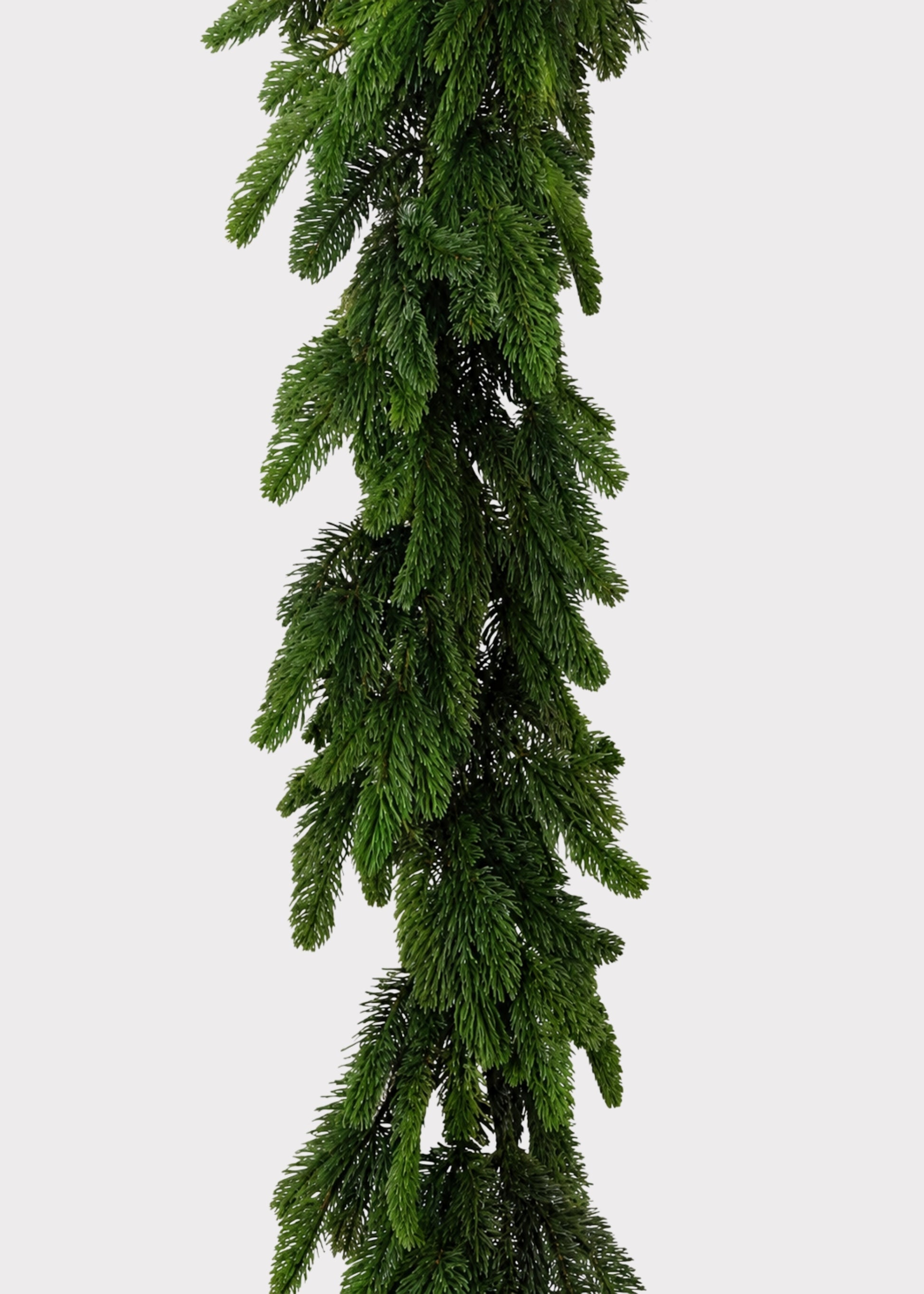 An artificial green fir garland hanging vertically against a plain light gray background.
