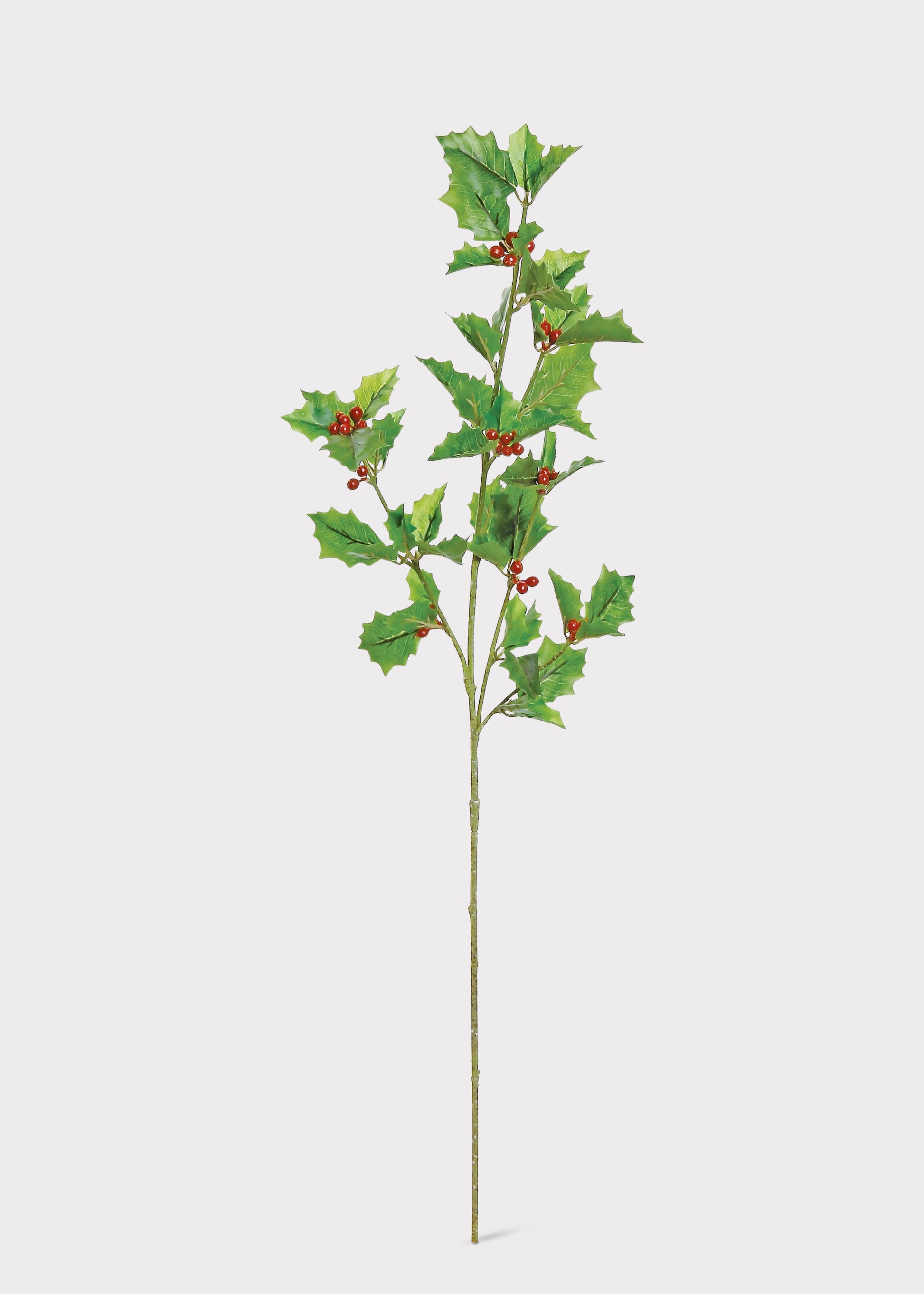 A single artificial holly branch with green leaves and small red berries on a long stem, photographed against a plain light gray background.