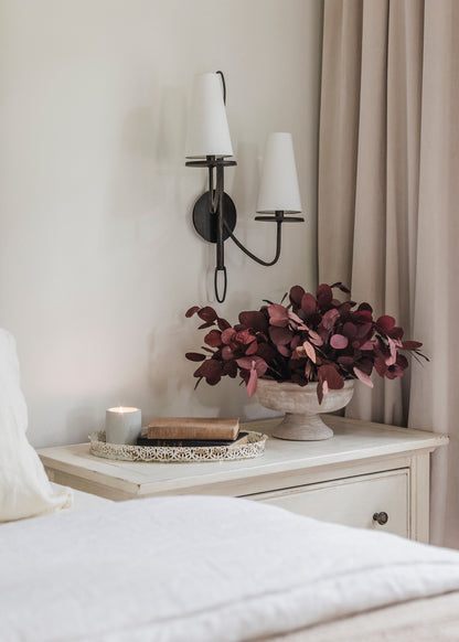 Decorative nightstand with a vase of preserved eucalyptus leaves in red