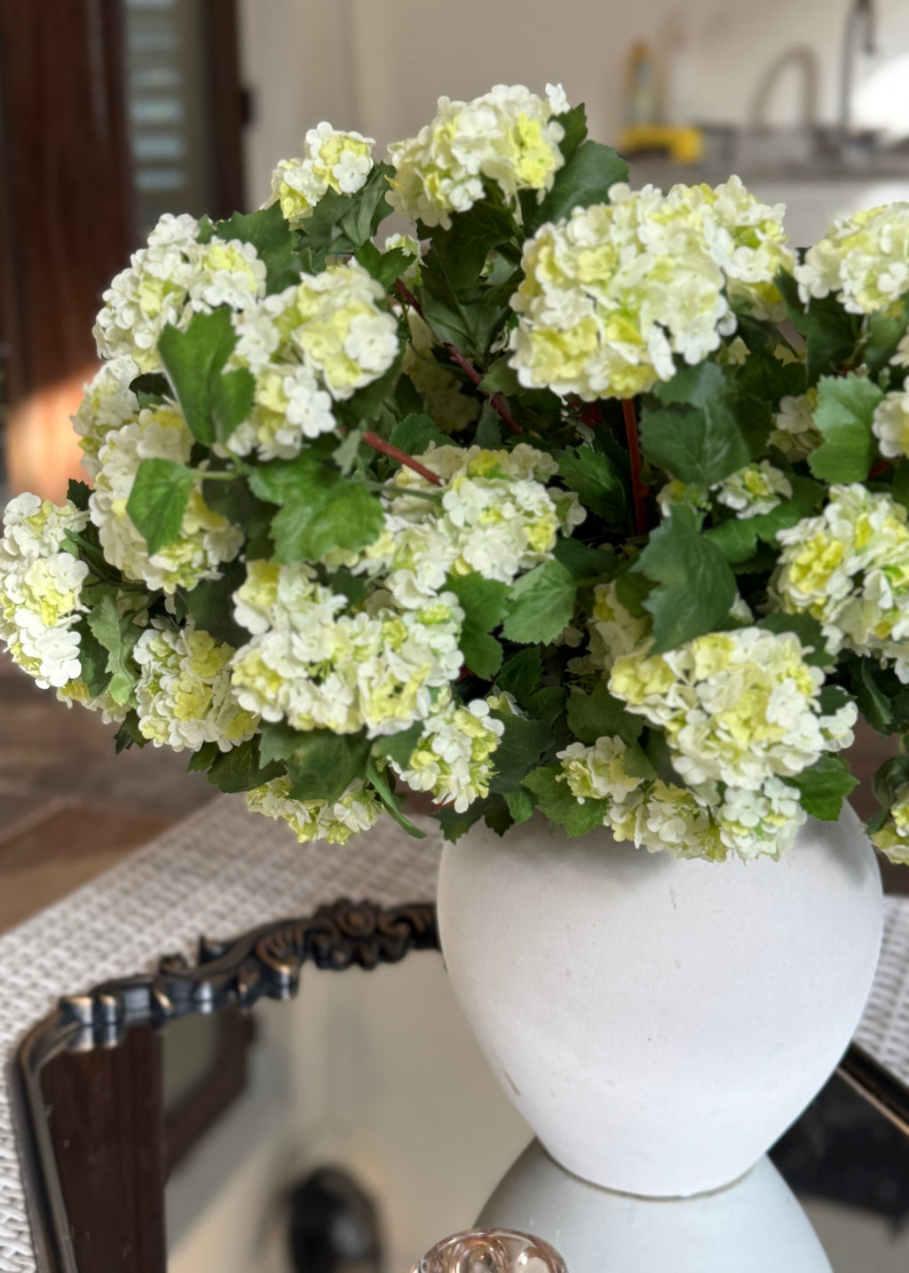 White vase with green snowball flowers 