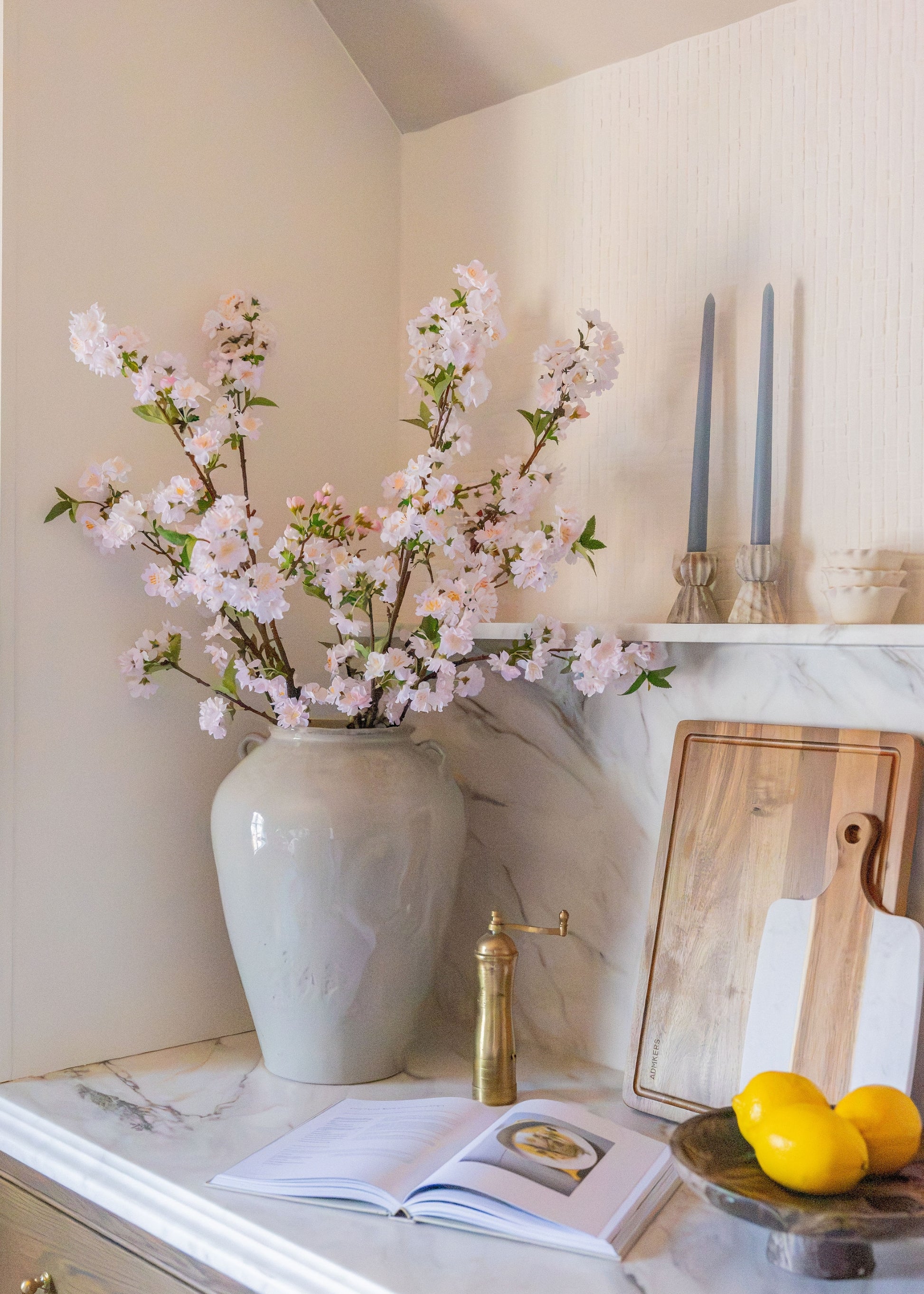 artificial cherry blossom stems styled in a vase on a kitchen counter