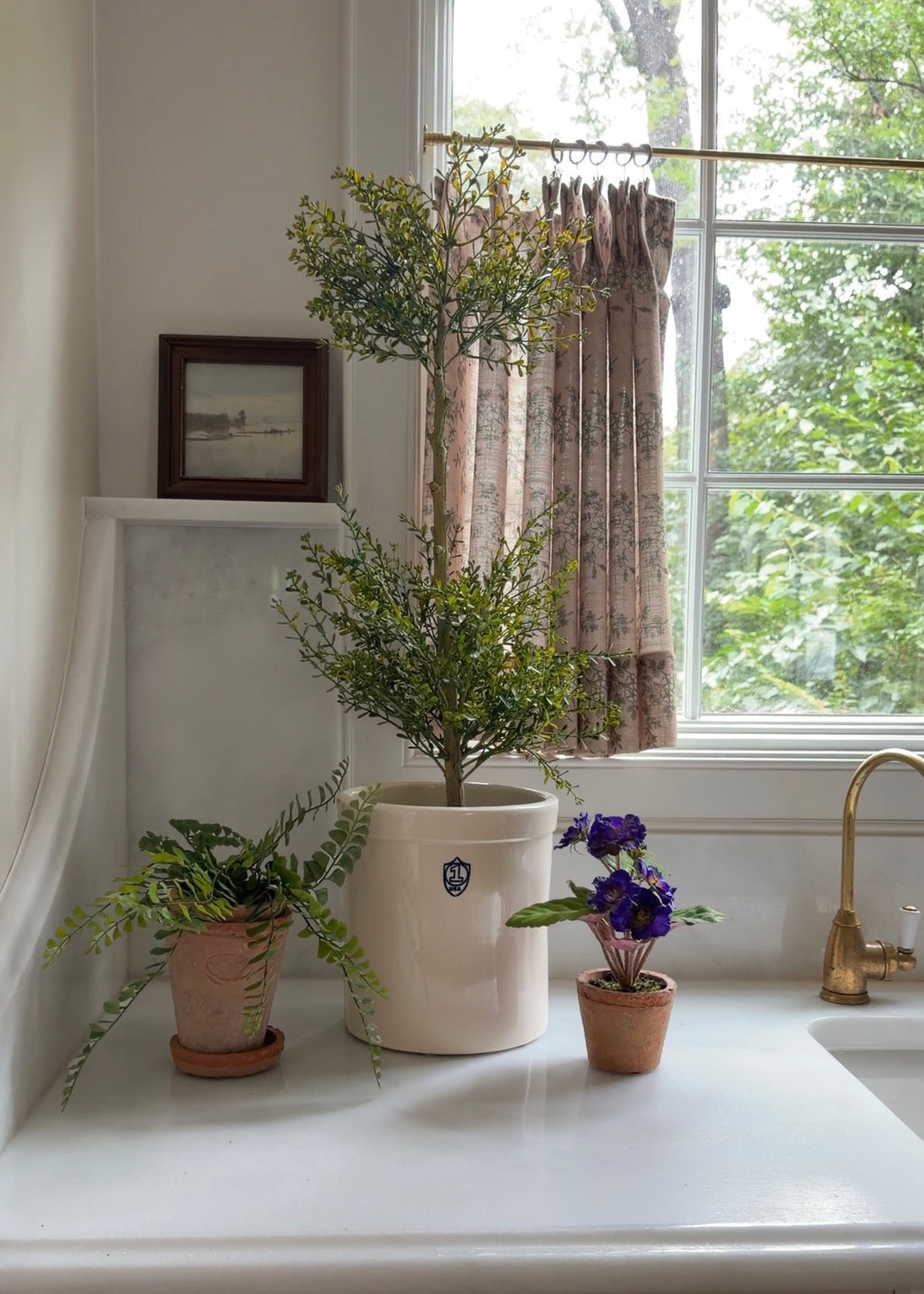 Potted faux topiary, violet and fern on a kitchen counter
