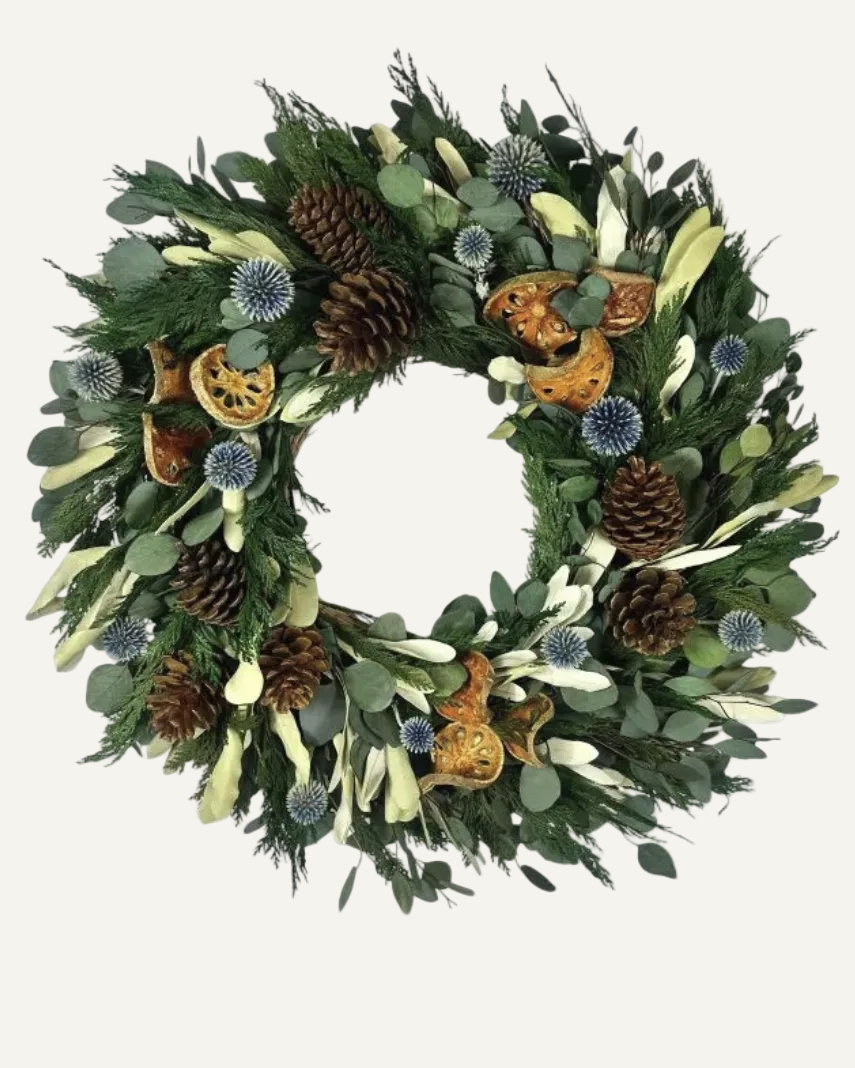 Decorative wreath with greenery, pinecones, and autumn-themed elements on a white background