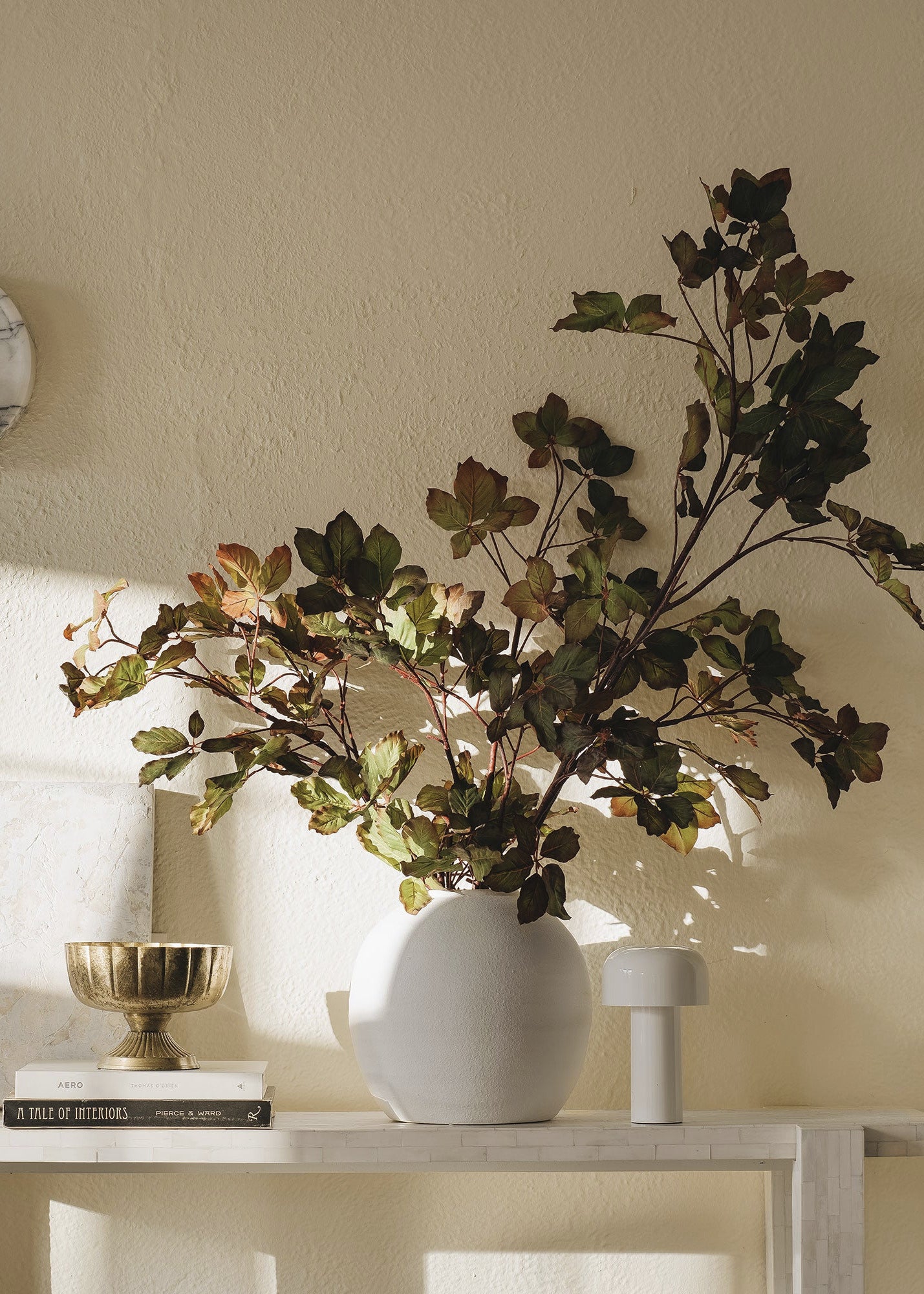 Decorative plant in a white vase on a table with a neutral wall background