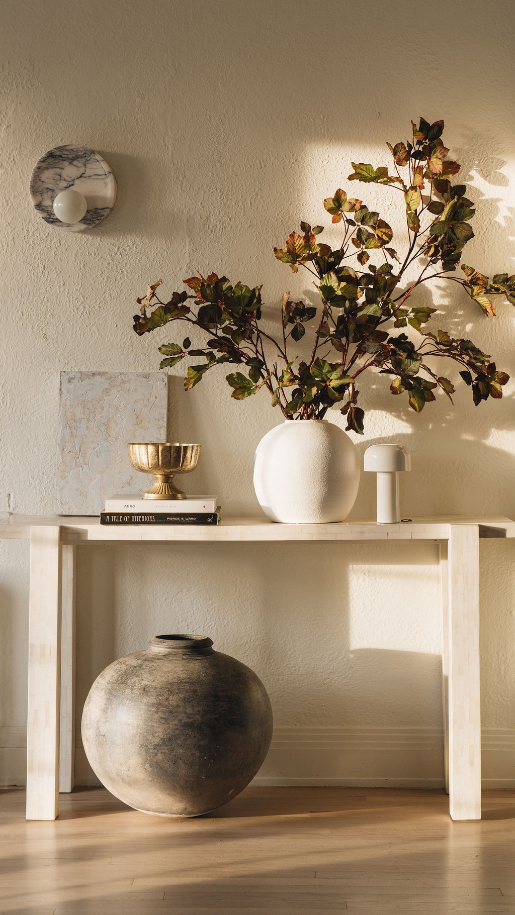 Decorative setup with a vase, books, and a plant on a table against a neutral wall.