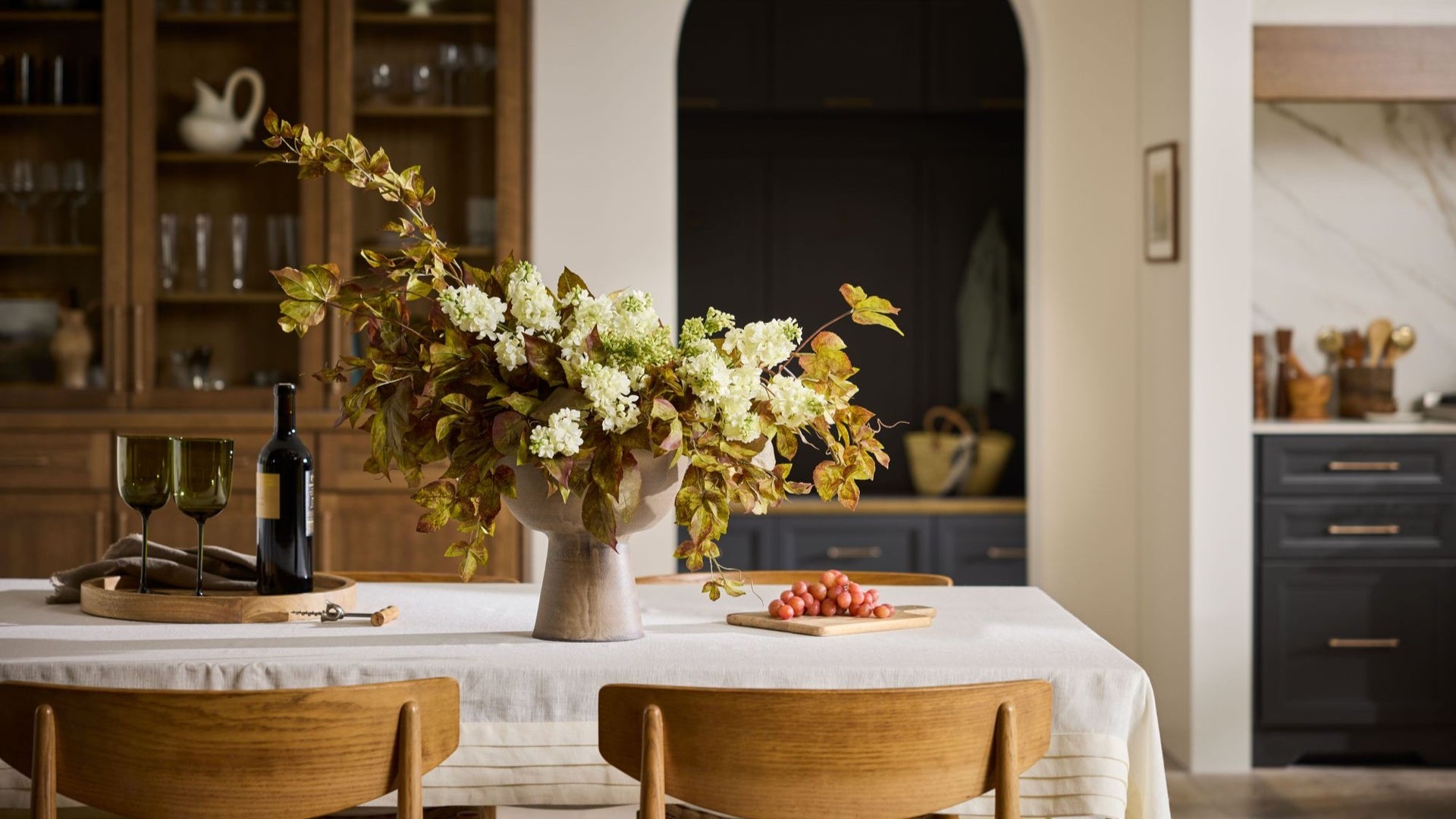 Dining room with a table set for a meal, flowers, and wine.