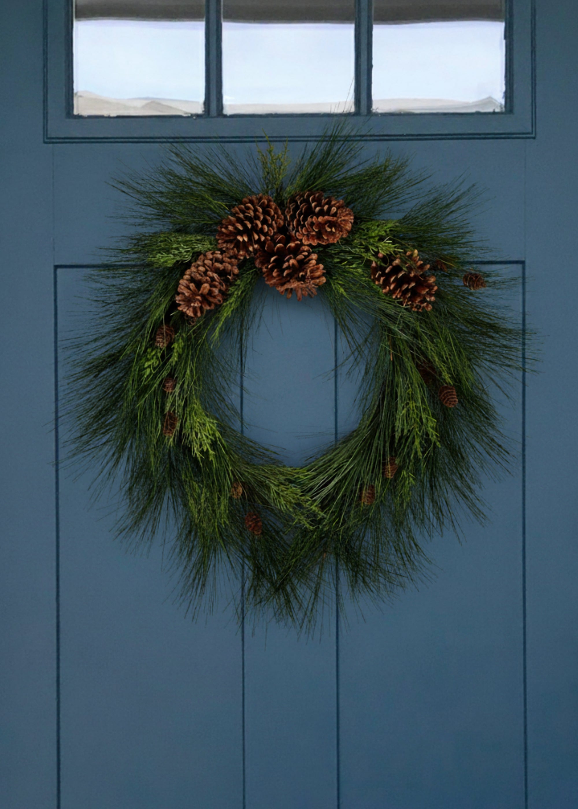 Faux long needle pine wreath with pine cones on blue door