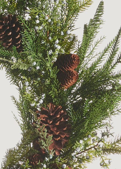 Close-up of a faux evergreen wreath with juniper berries and pine cones