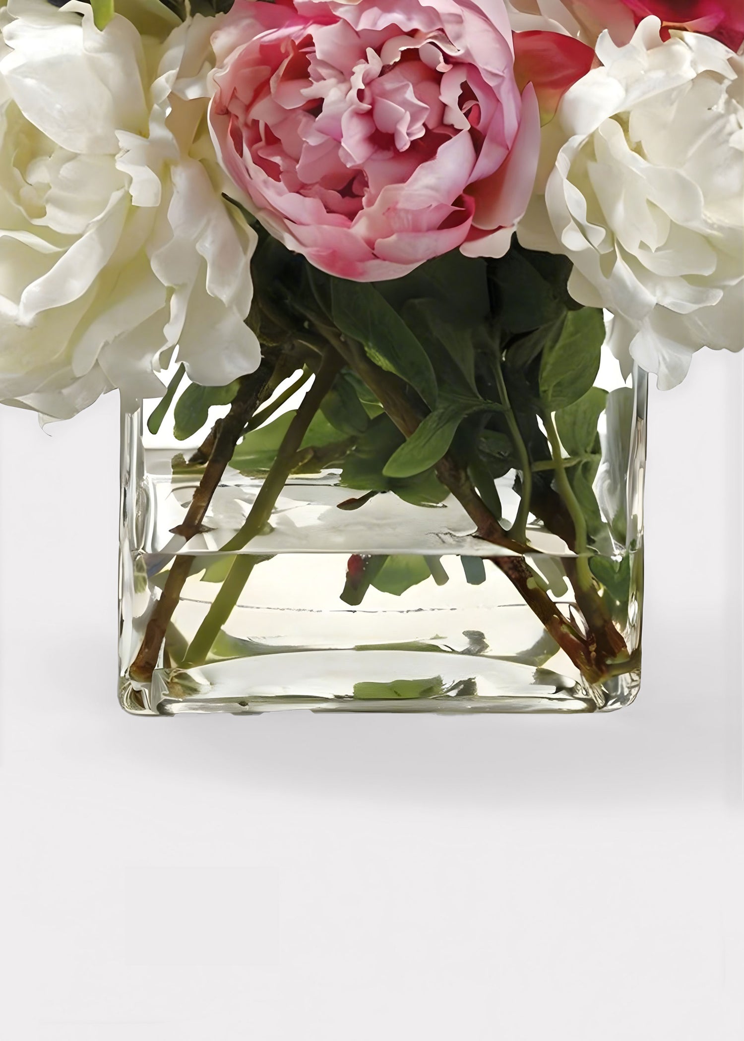 Clear glass vase with fake water and pink and white flowers peonies
