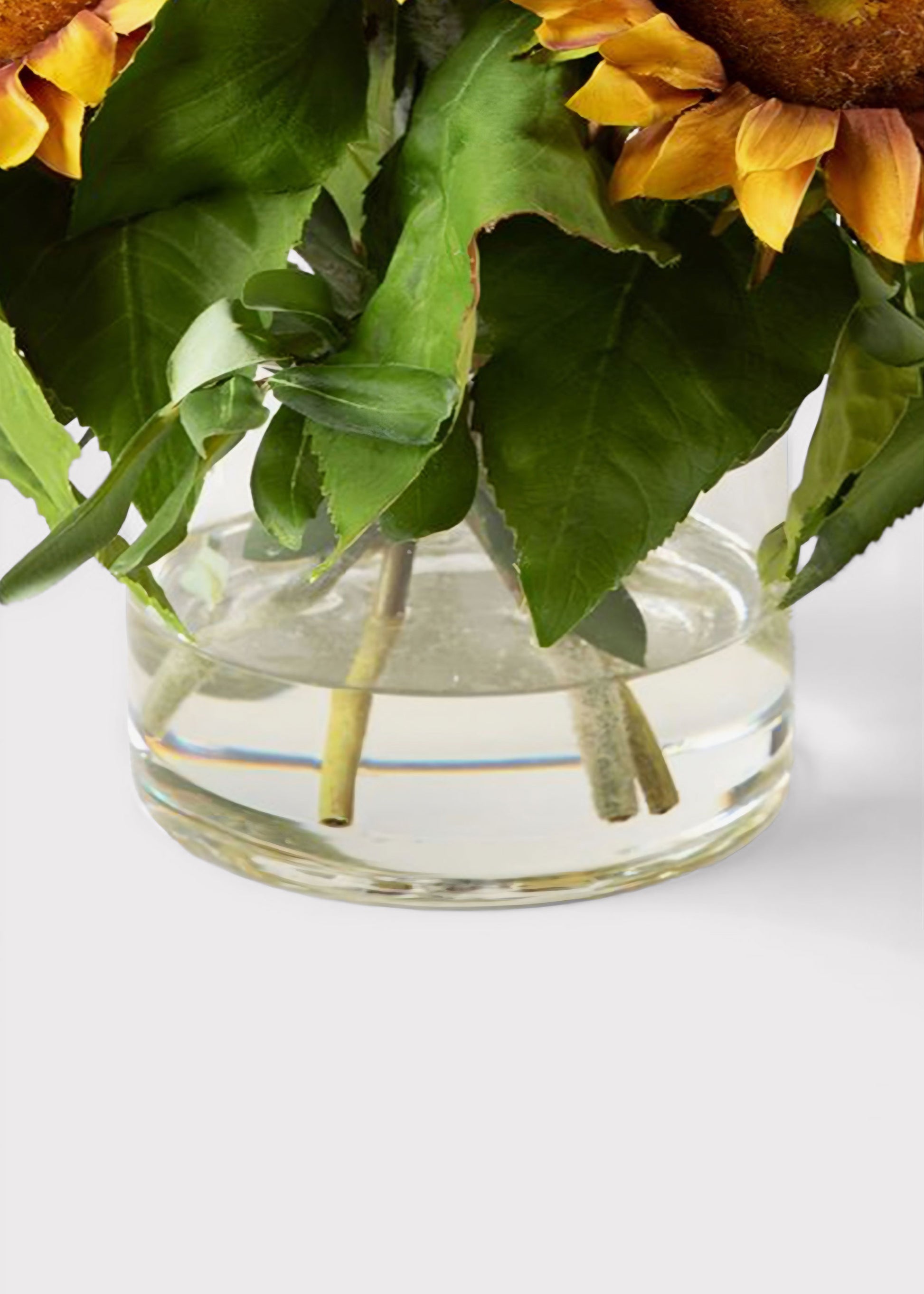 Clear glass vase with artificial water and sunflowers 