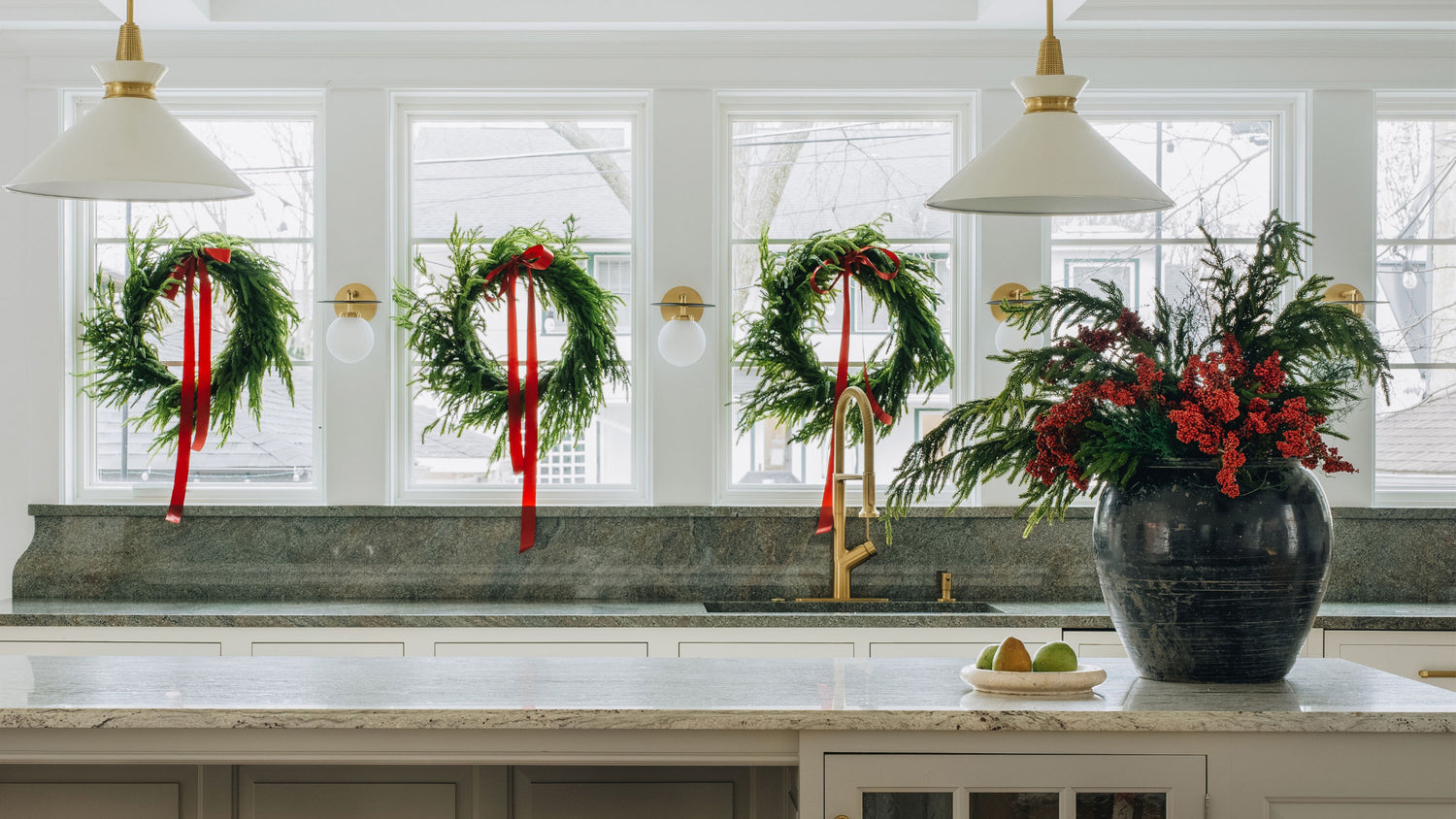 Holiday Kitchen with Norfolk wreaths hanging on the windows and a Norfolk and berry flower arrangement