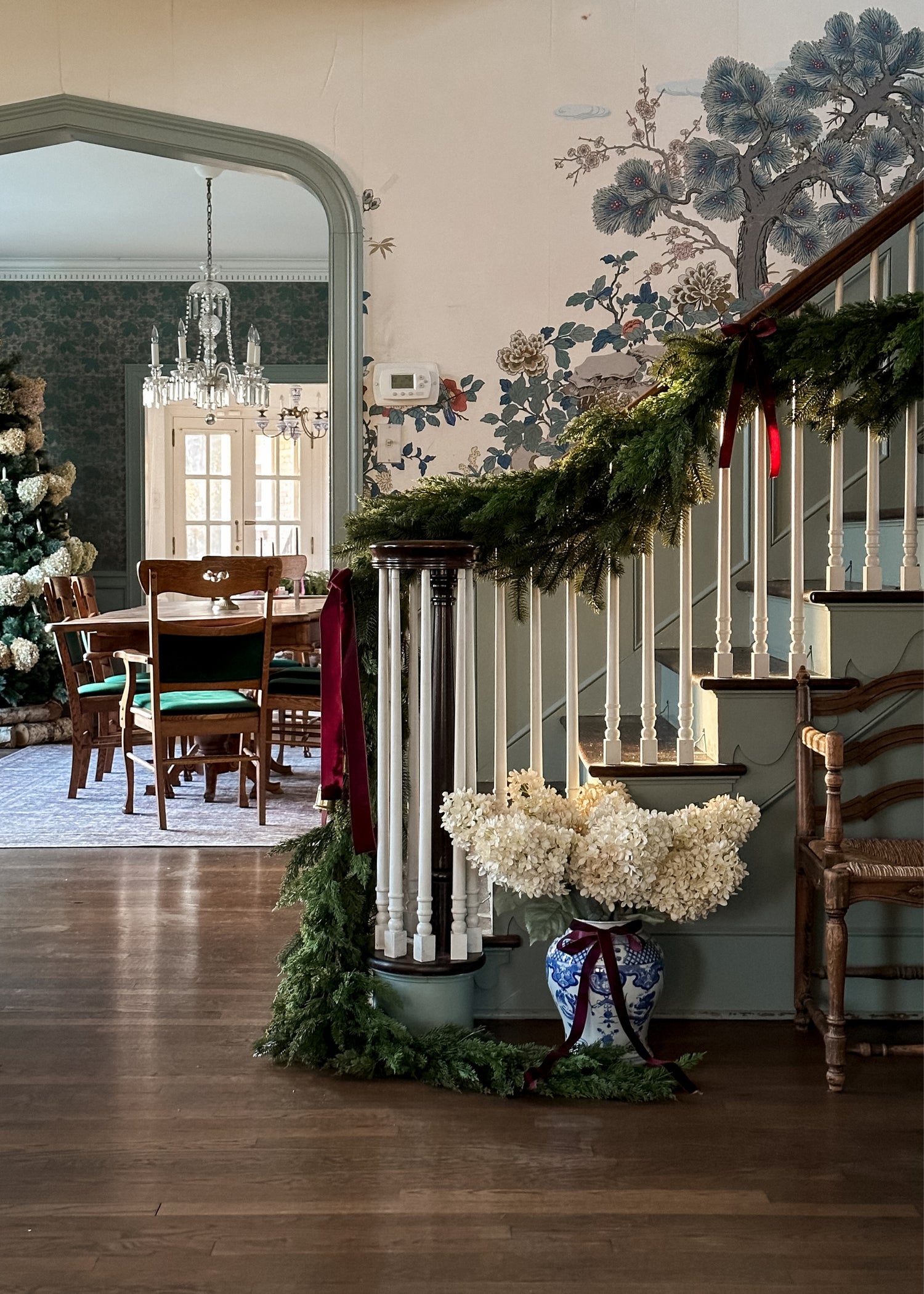 Decorative staircase with cedar greenery garalnd and a vase of parchment hydrangeas in a home 
interior.
