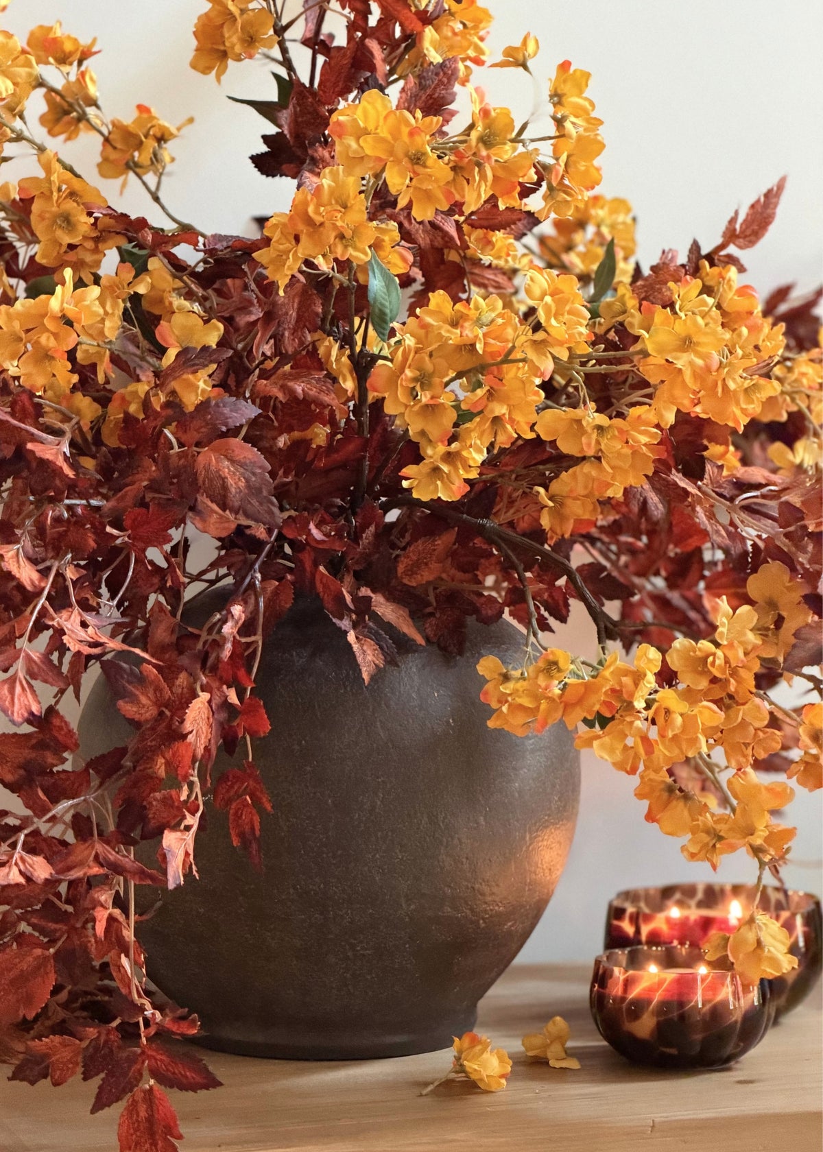 artificial cimicifuga leaves in brown and autumn yellow cherry blossoms arranged in a stoneware vase
