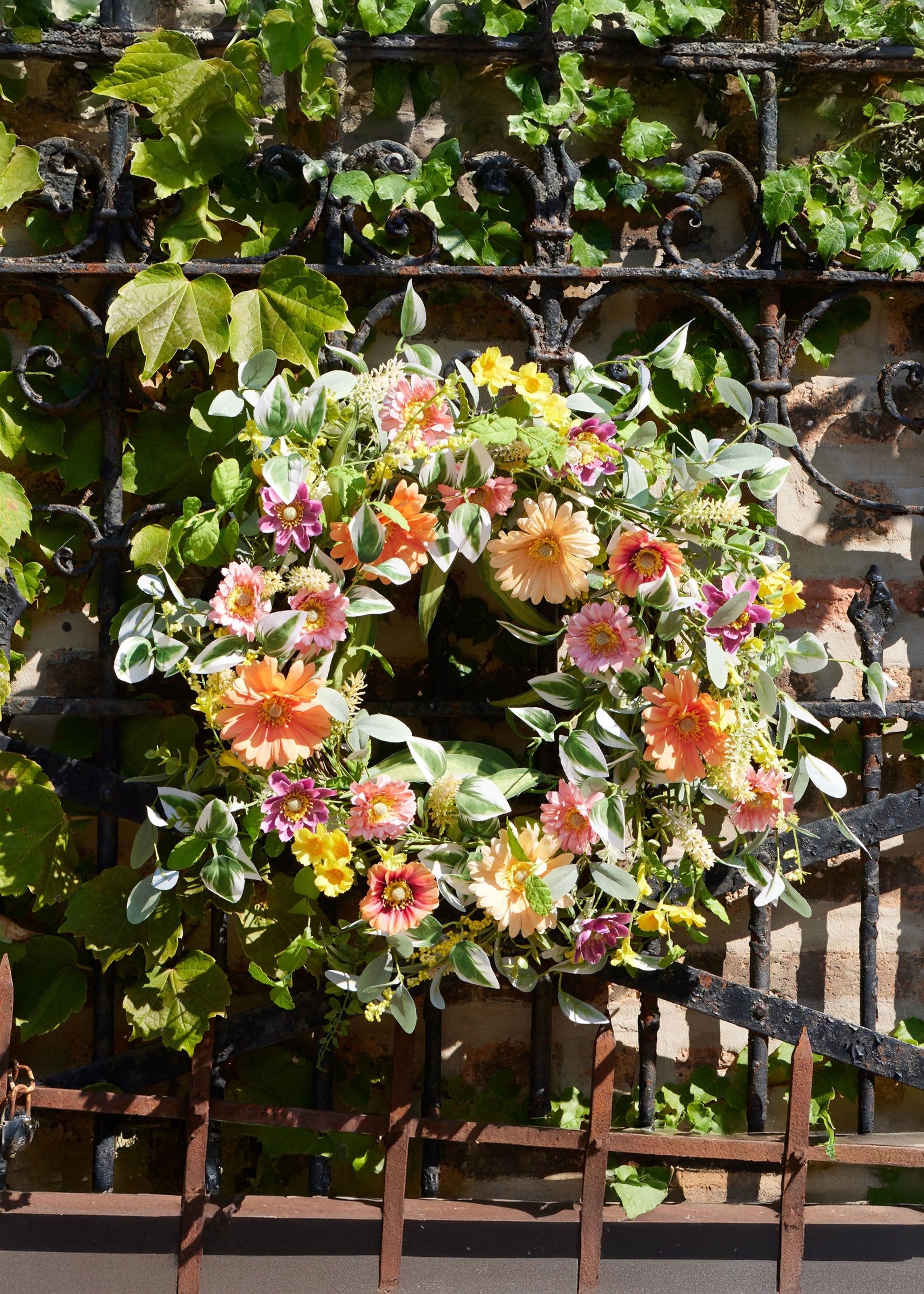 gerbera daisy wreath hanging on iron fence
