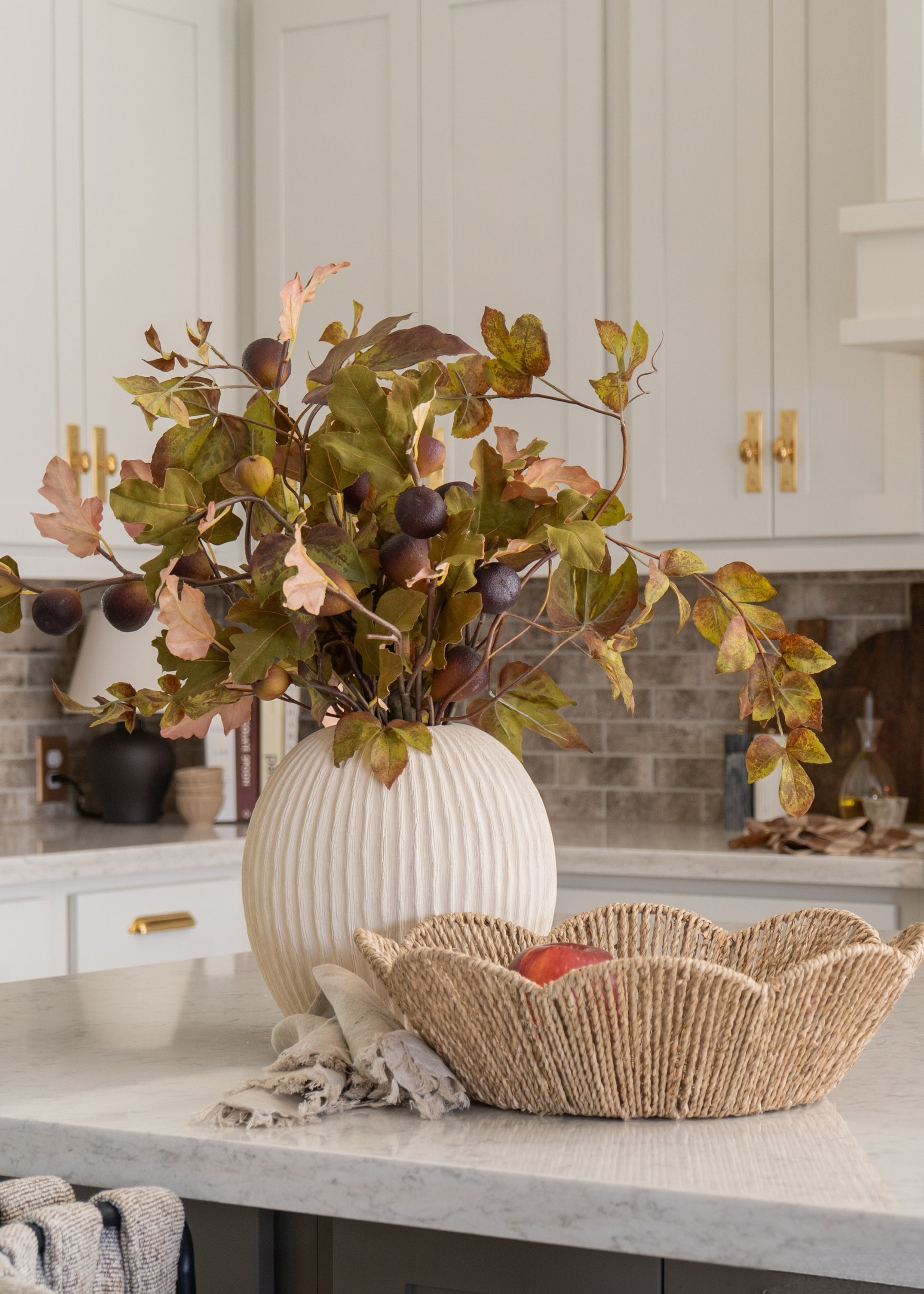 Decorative vase with autumn-themed arrangement on a kitchen counter