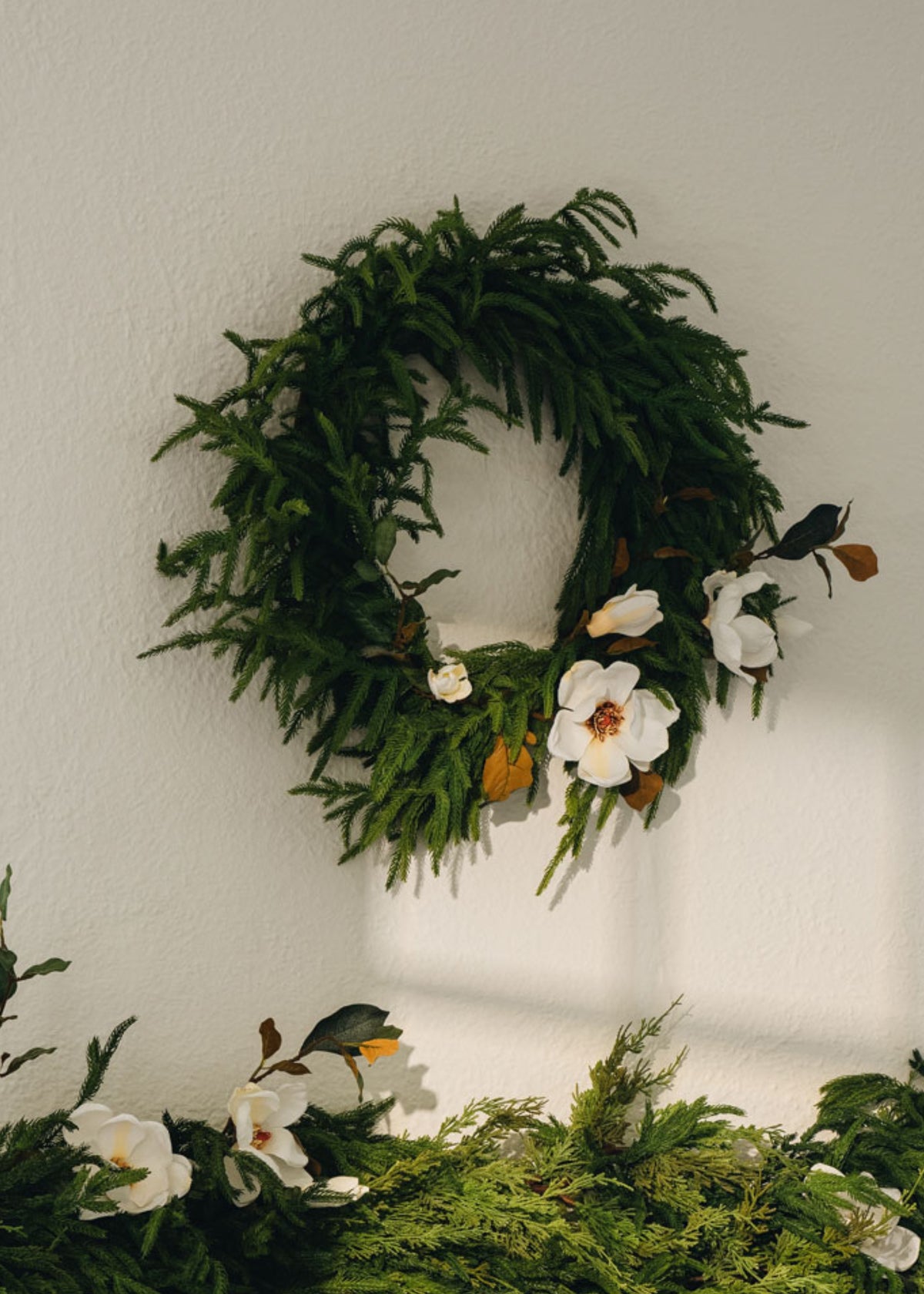 afloral norfolk pine wreath styled with faux magnolias
