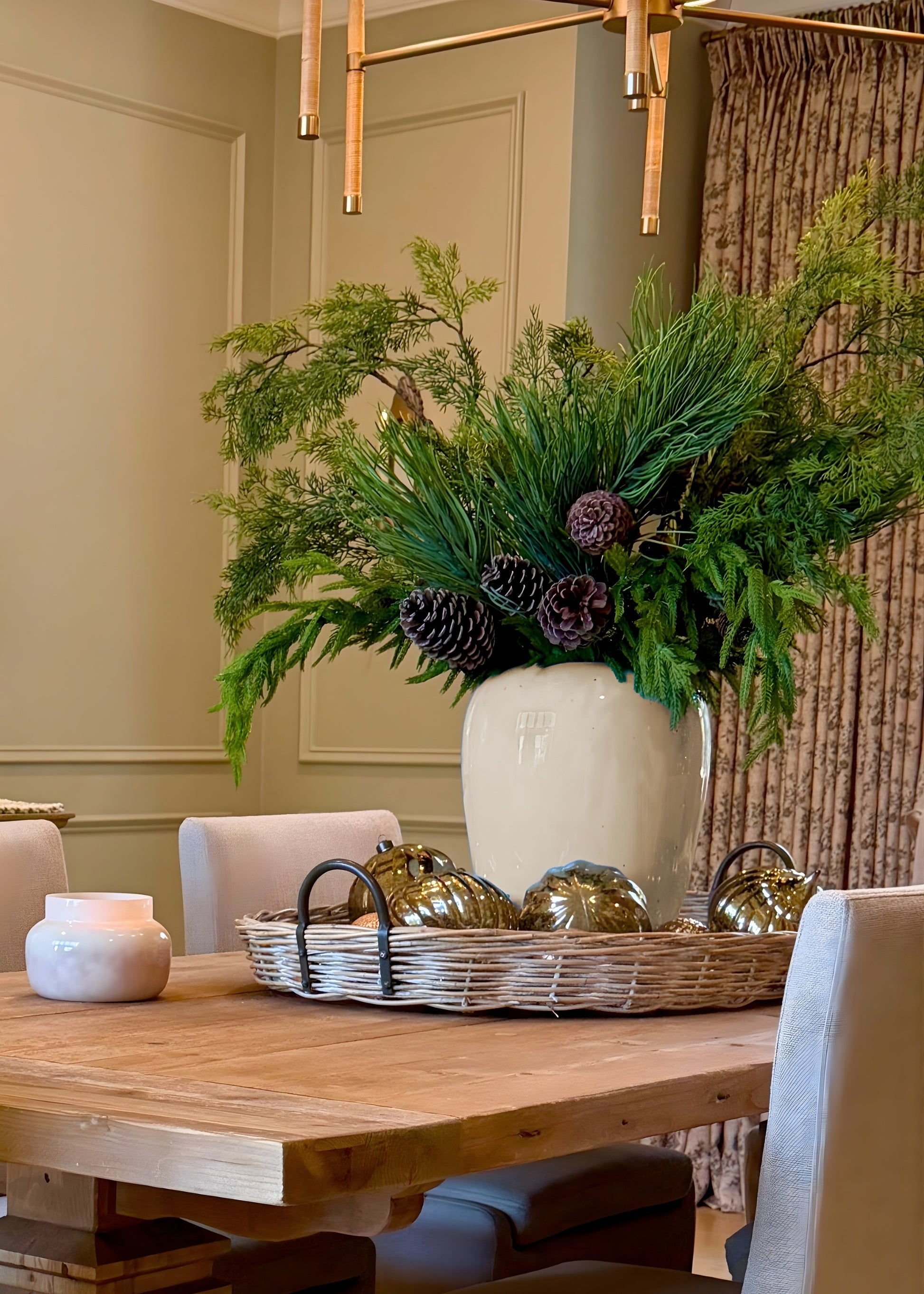 Dining room table with decorative vase arranged with evergreens and norfolk pine