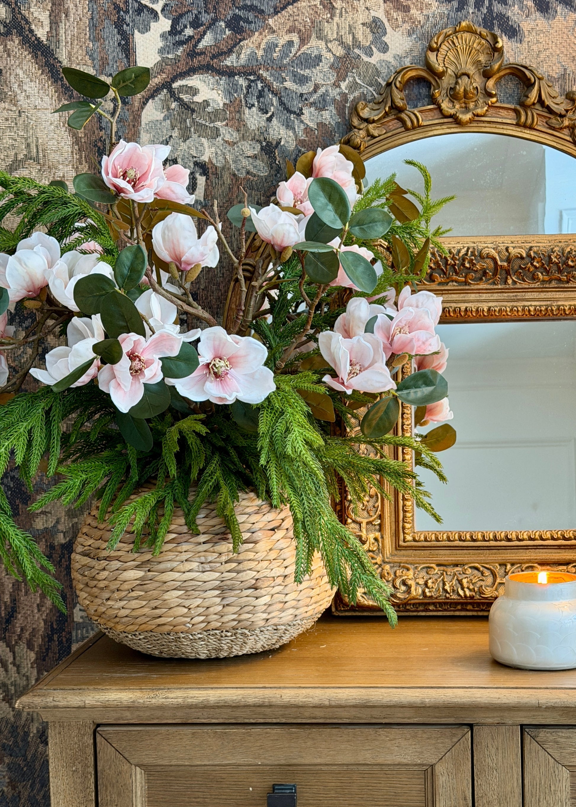 Decorative setup with a basket of magnolia flowers and norfolk pine