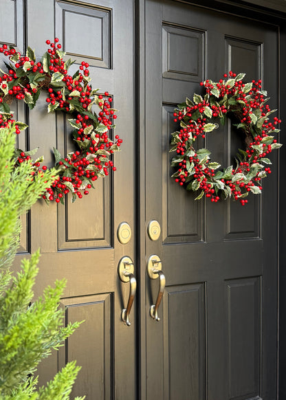 Decorative wreaths with red berries and holly on double doors