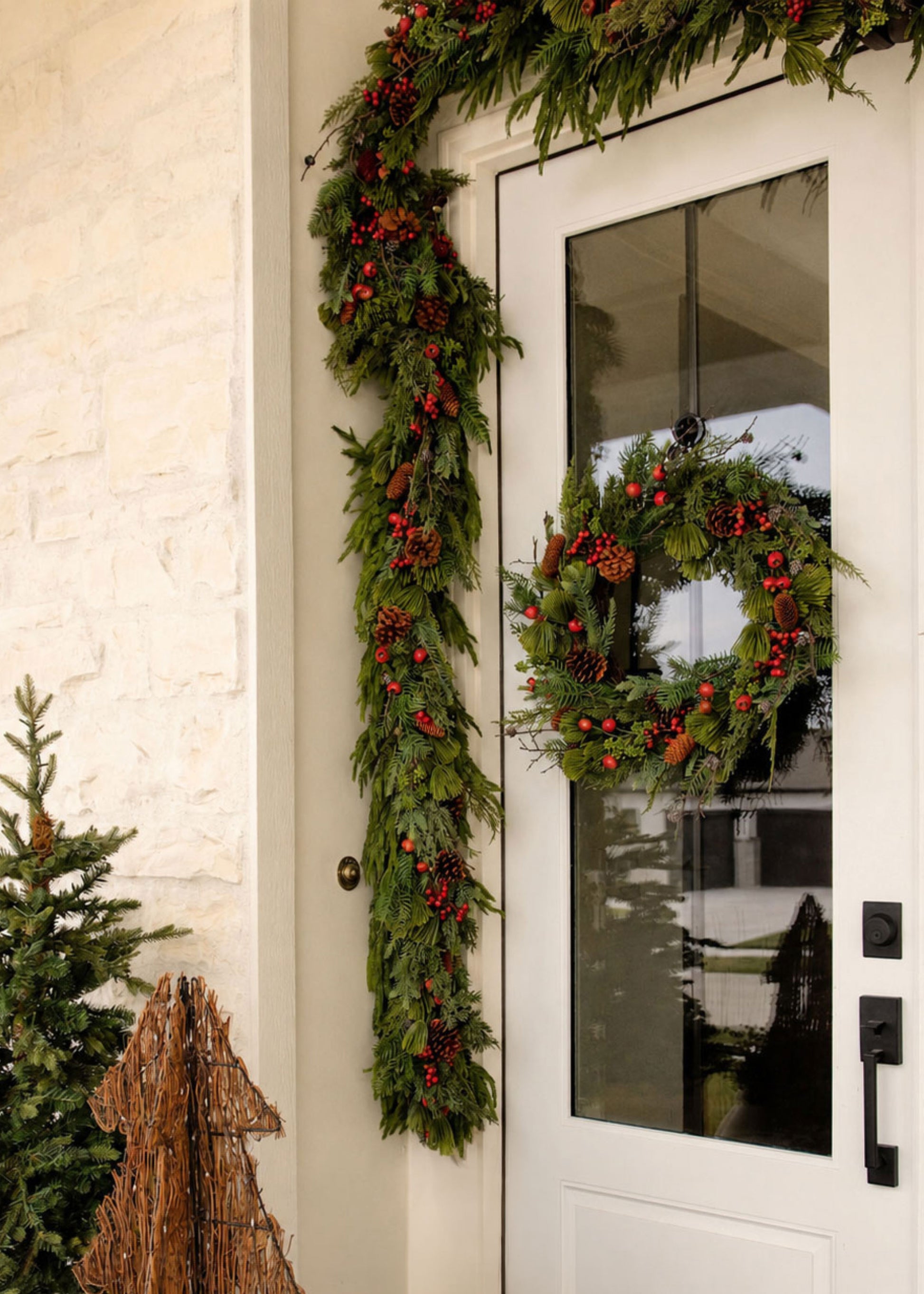 Decorative Christmas wreath and garland on a door with pine cones and berries